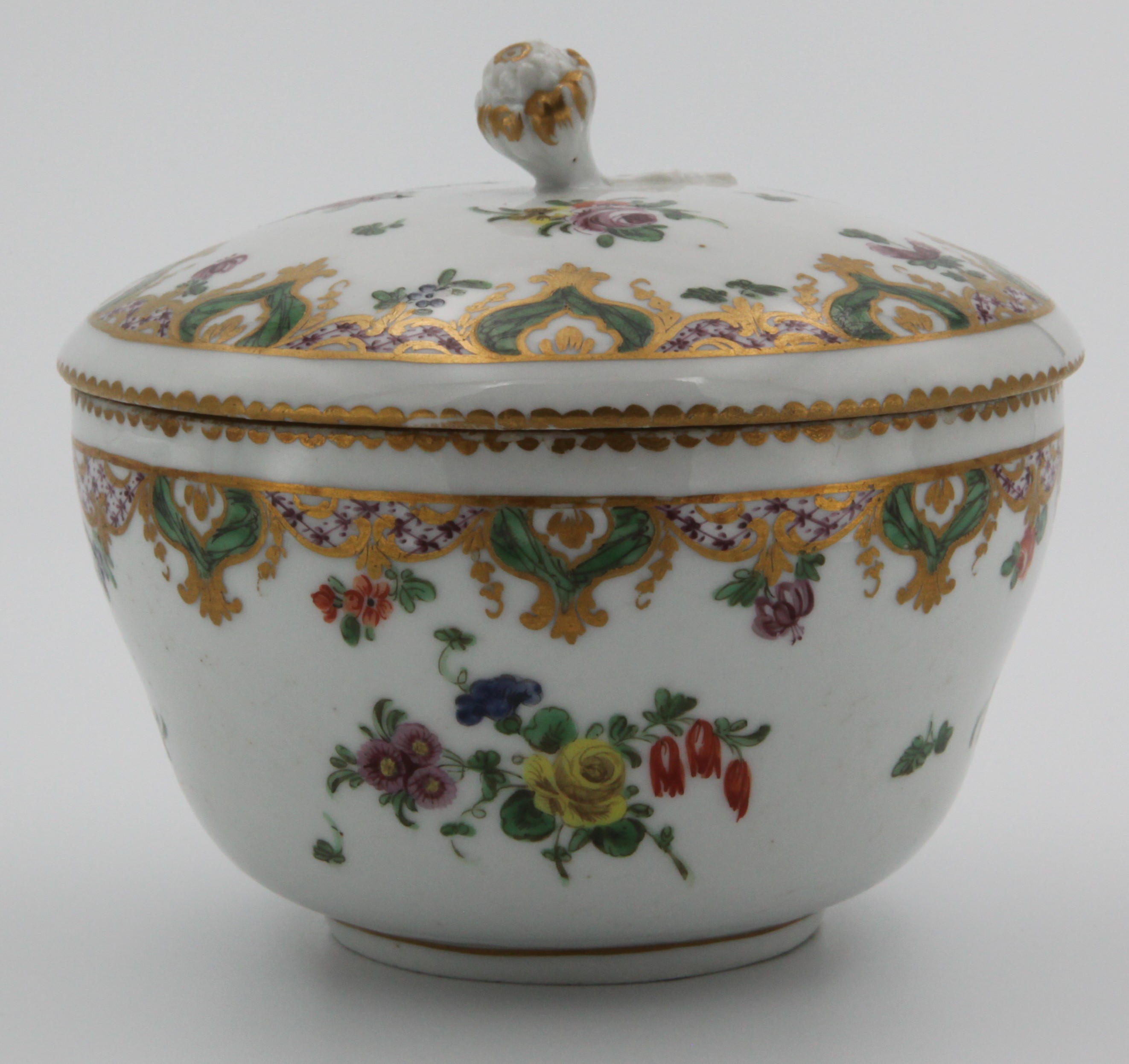 A Bristol ogee-shaped sucrier and cover, with flower and leaf knop, painted in coloured enamels in Ludlow service style, with flower sprays, within puce scale borders, with green and gilt cartouches of leaves and pendant flowers, circa 1775, no mark.