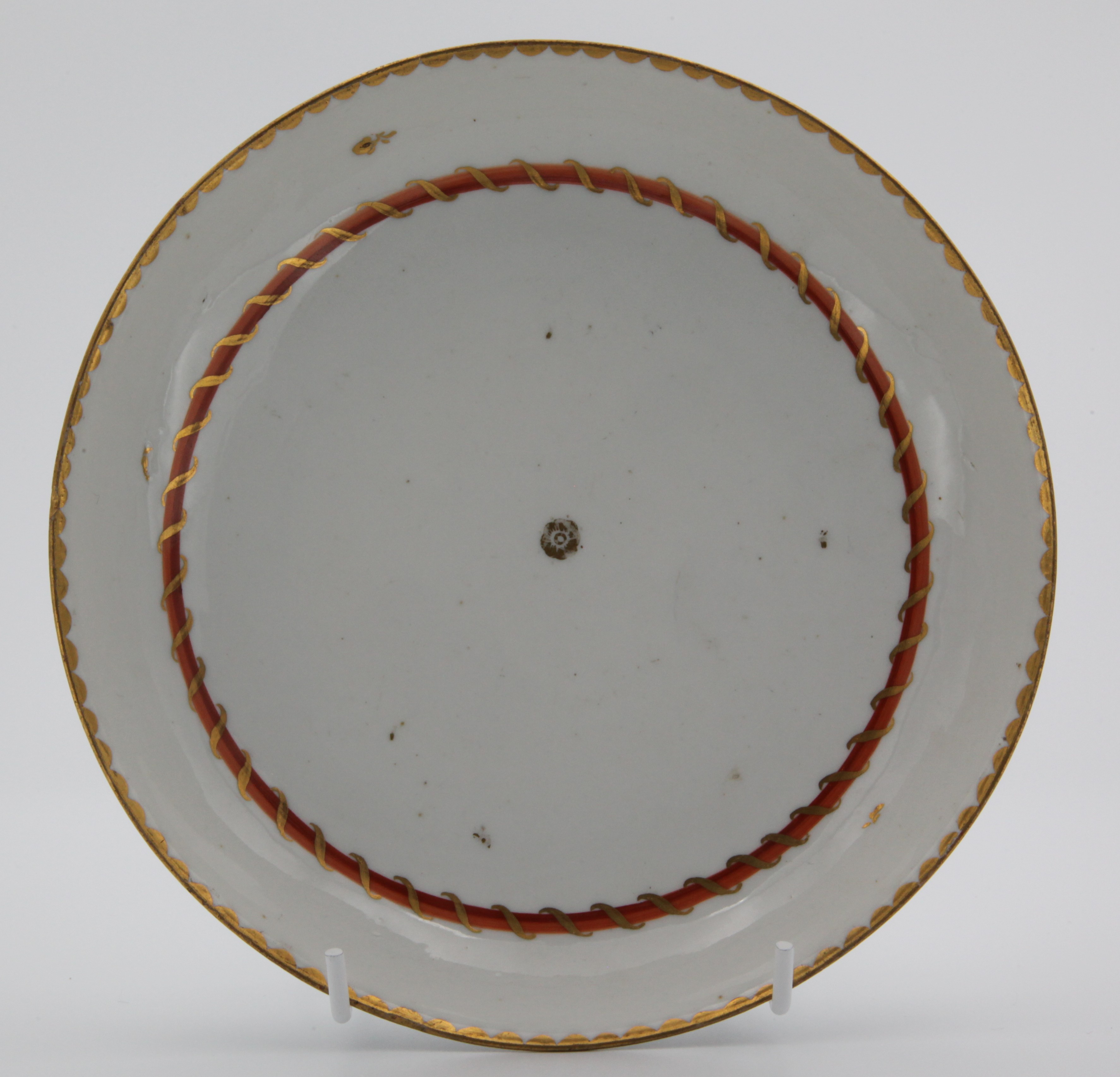 A stand for Bristol teapot (1209) of plain round form, painted in enamel with orange, red and gilt entwined bands (the pattern of the Pitt service) with gilt dentil rim, central roundel and scattered leaves, circa 1775, painted blue X3. mark, the 3 distincitive