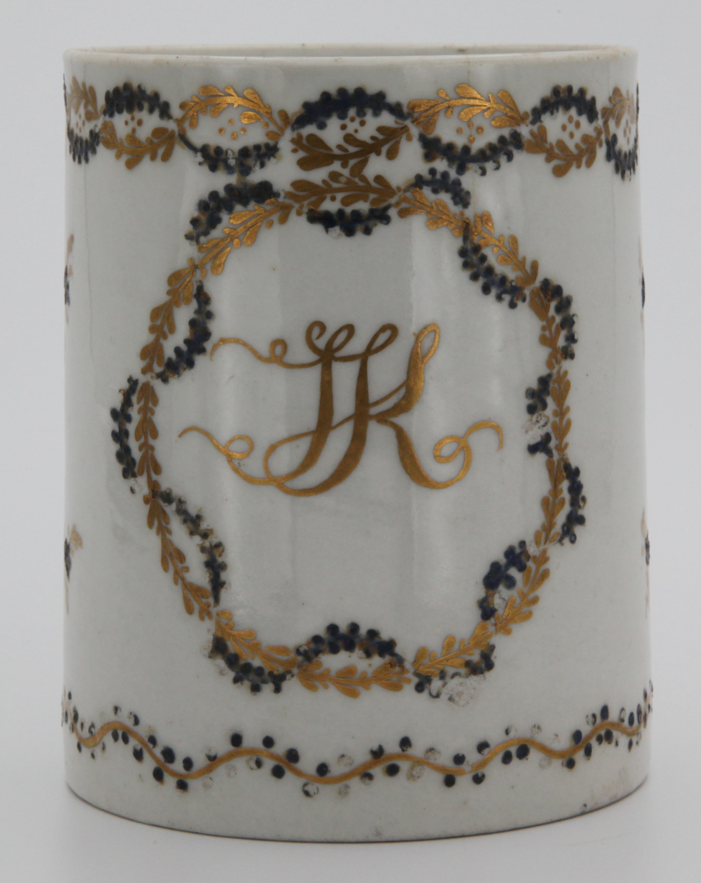 A rare Bristol cylindrical mug, with harebell moulded ear shaped handle, painted in gilt,with the entwined monogram 'JK', within a black and gilt entwined leaf roundel, and with scattered black and gilt flowers, within entwined borders, circa 1774, no mark.