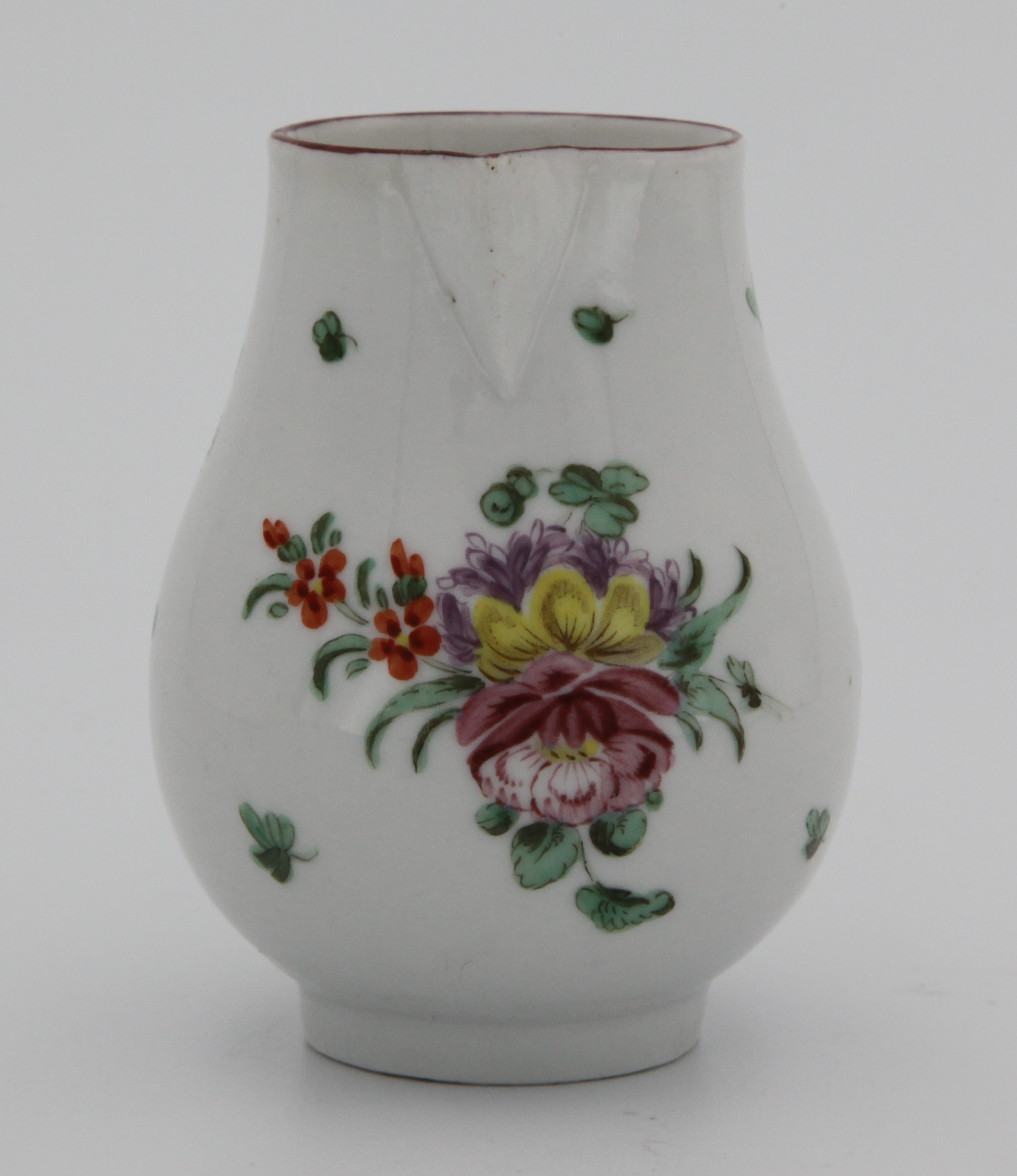 A Bristol baluster shaped sparrow beak cream jug, with loop handle, painted in coloured enamels with a spray of flowers and leaves, and scattered flowers, brown line rim, circa 1775, no mark.