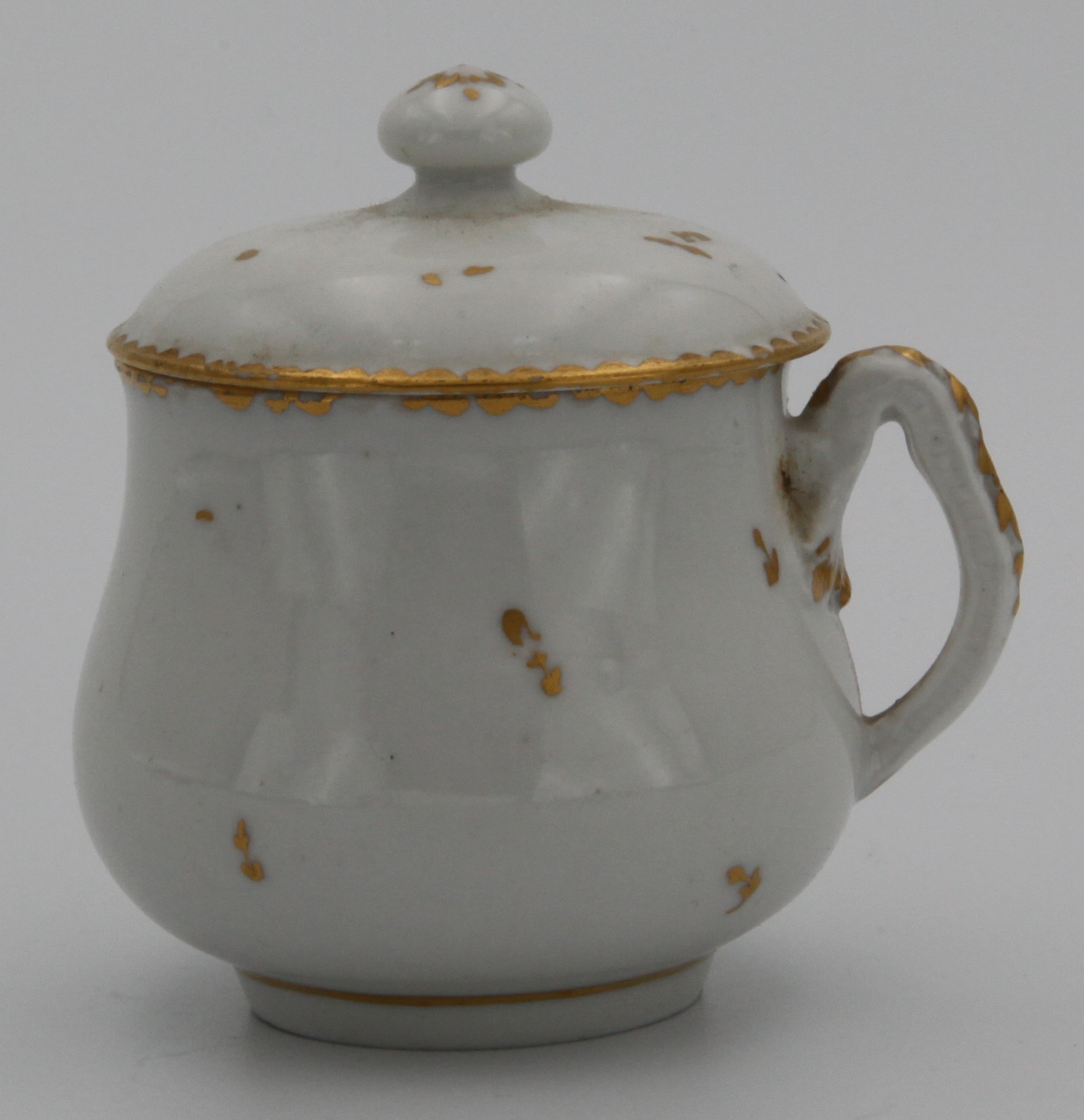 A rare Bristol custard cup and cover, with squashed loop handle oulded with harebells and gilt decorated, painted in gilt with scattered flowers, slightly domed cover, ball finial with gilt roundel, marked with an X, c. 1770