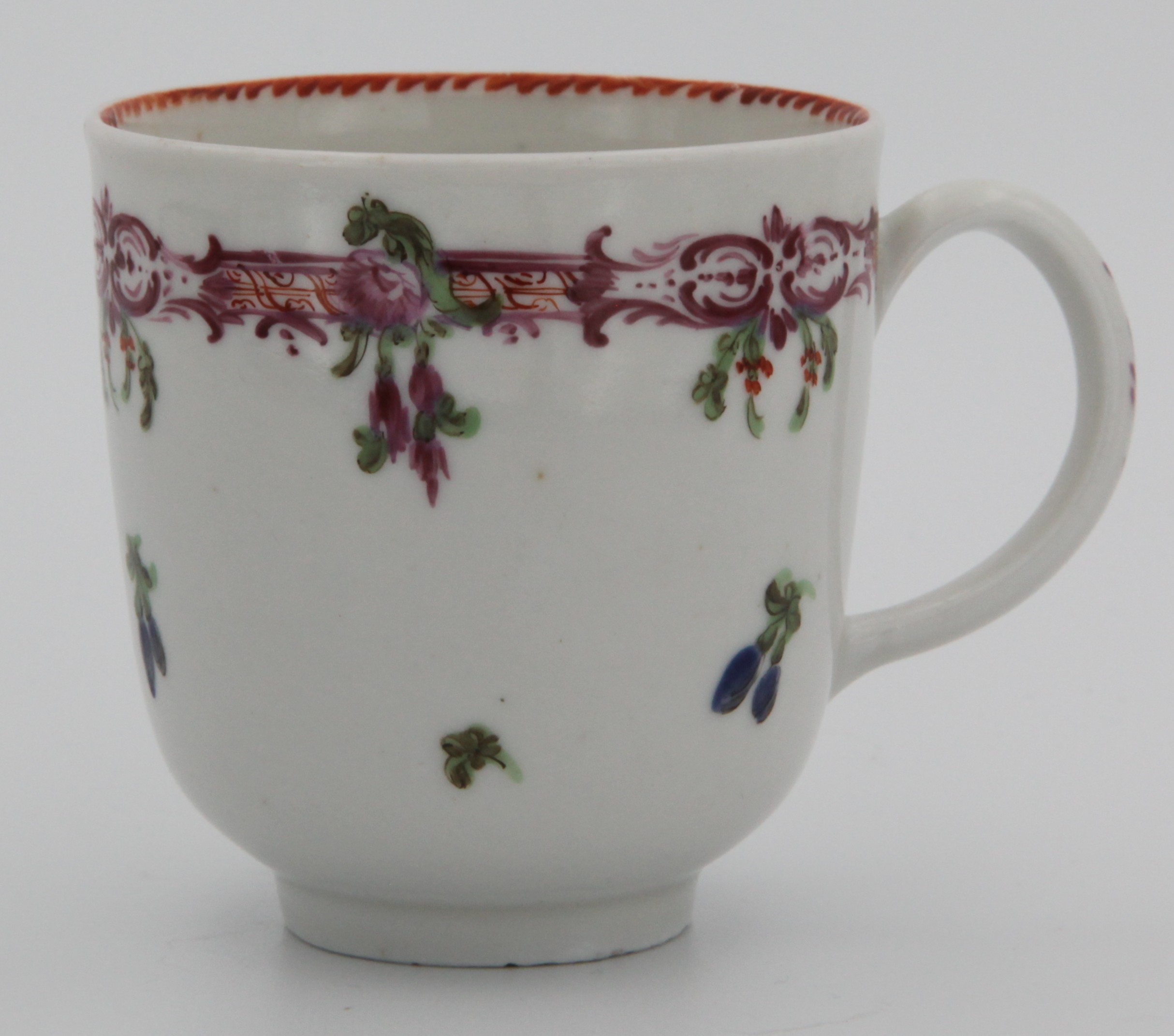 A Bristol coffee cup, painted with a stylised puce band,  hanging leaves and flowers above scattered flowers, angular orange dentil rim to the inside. c. 1770. No mark.