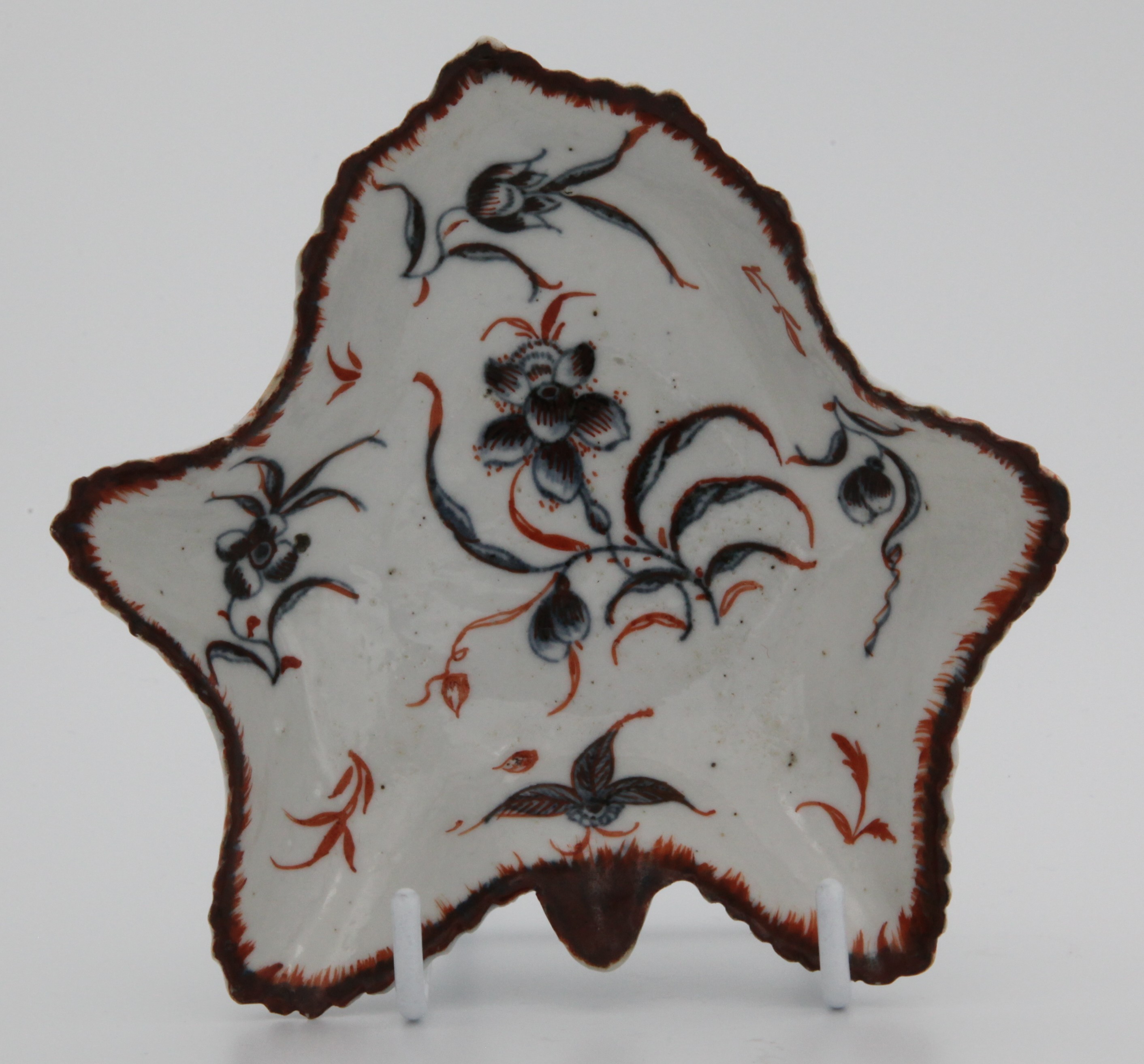 A Plymouth leaf-shaped pickle dish, painted with flowers in underglaze blue, picked out in overglaze red, the underside in relief. c. 1770. No mark