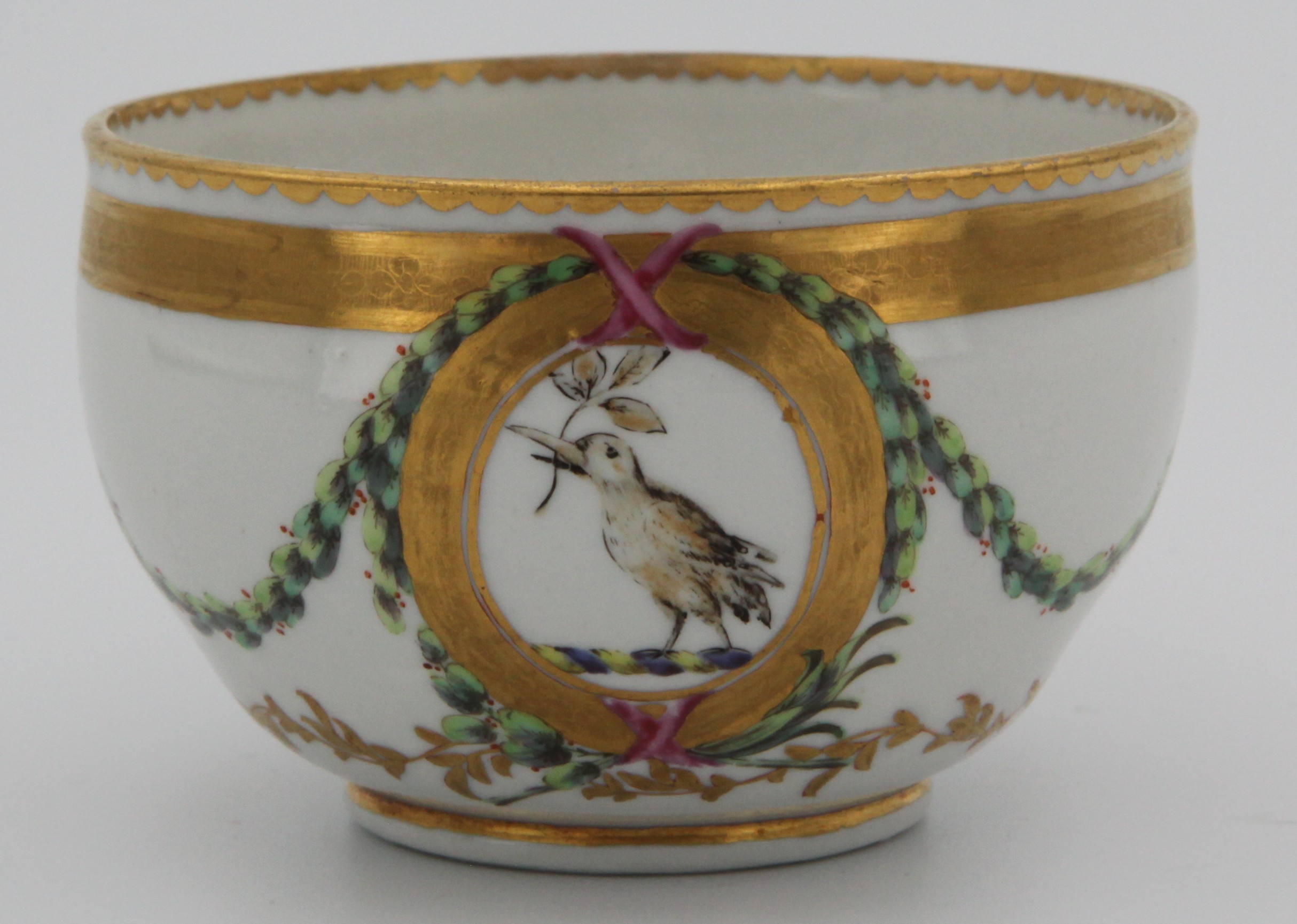 A Bristol ogee shaped teacup, from the Chough Service,  painted with a bird crest, with leaves in its beak, probably for Tothill of Peamore, Devon, within oval cartouches, and with sepia profile medallions, united by laurel swags, within gilt tooled, leaf and dentil bands, circa 1774-75, blue painted X marks. See F S Mackenna, Plymouth and Bristol Porcelain, page 68, plate 27, for a plate from this service.