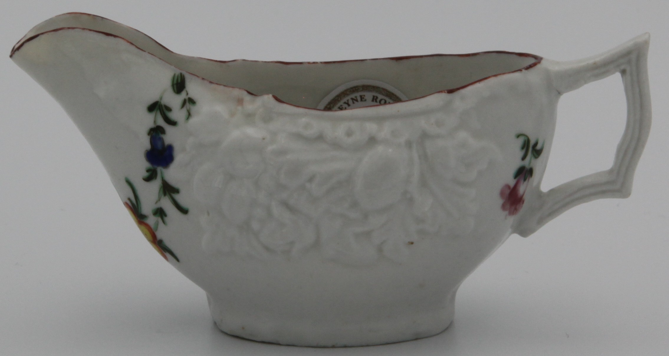 A small Bristol butterboat with flattened angular handle, moulded with fruit and painted with a garland of flowers and two small pink sprays under and iron red rim, X11 mark, circa 1775