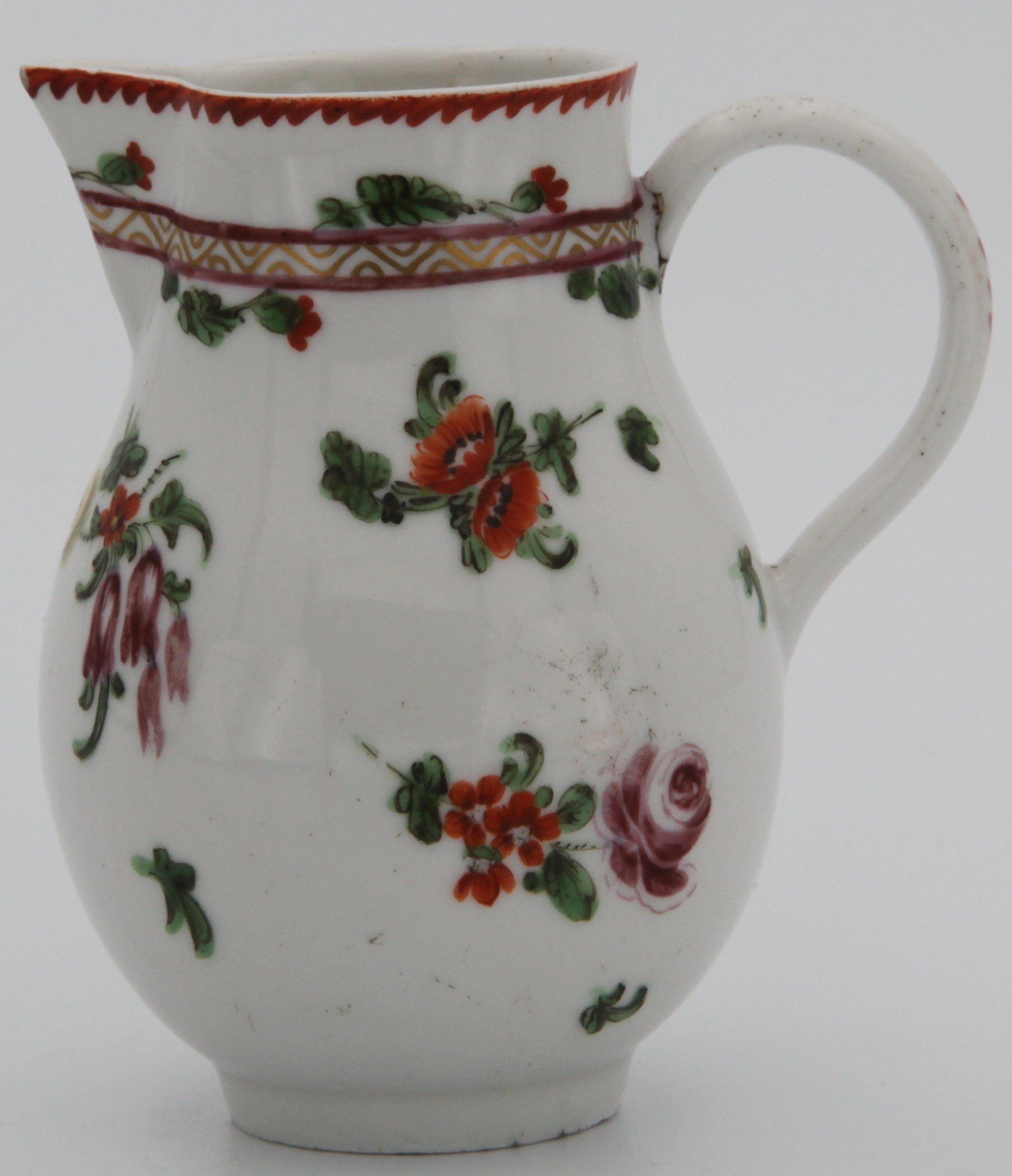 A Bristol sparrow beak cream jug with plain handle decorated in puce, painted in enamels with floral sprigs, a puce and gilt band  interwoven with orange-flowered sprigs under an iron red notched rim line, no mark