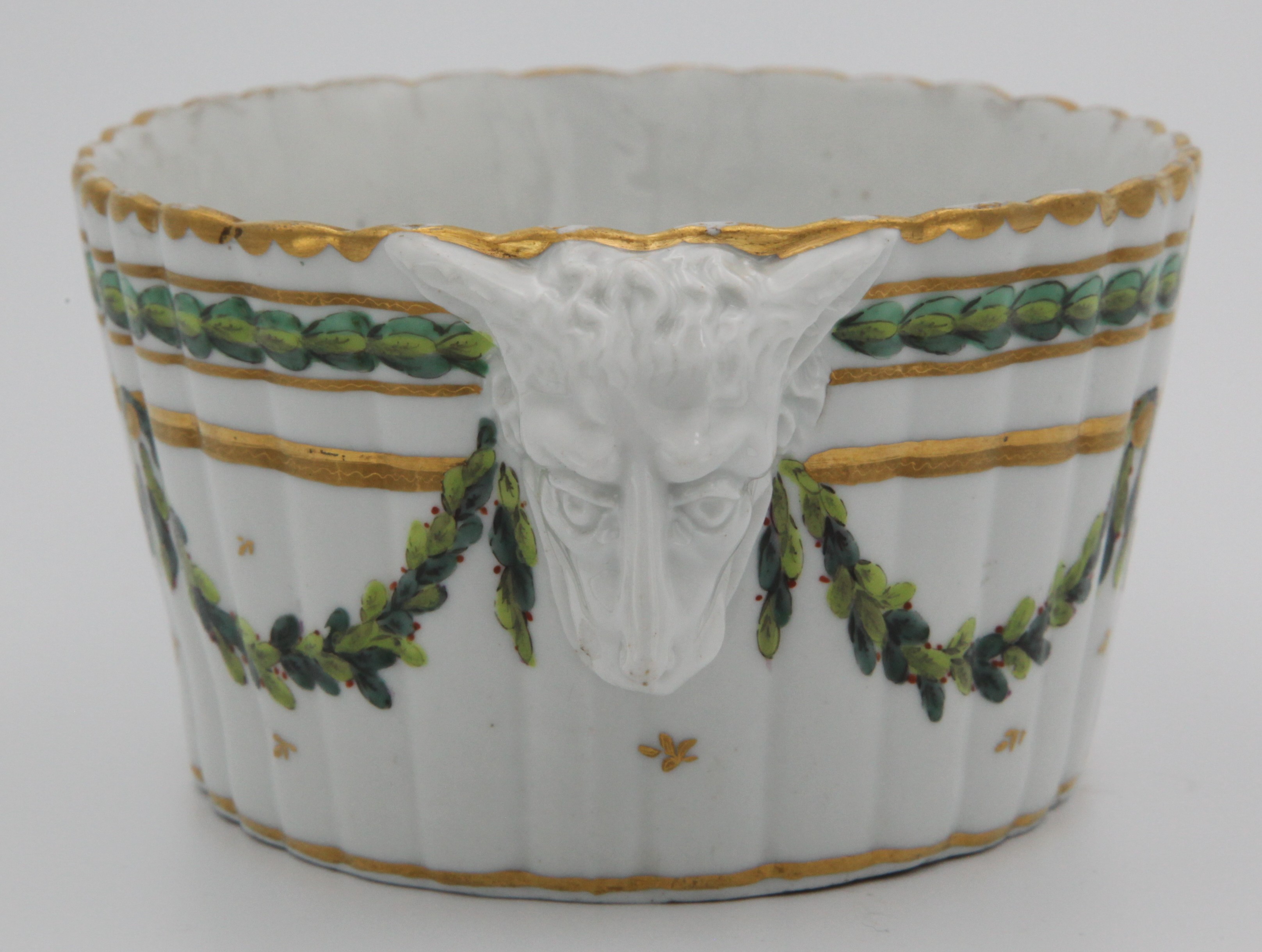 A rare Bristol fluted oval butter tub, with two crisply modelled fox mask handles, painted in green and iron red with laurel garlands, suspended from a gilt band, beneath laurel and gilt dentil borders, circa 1775, blue painted X and 11. marks