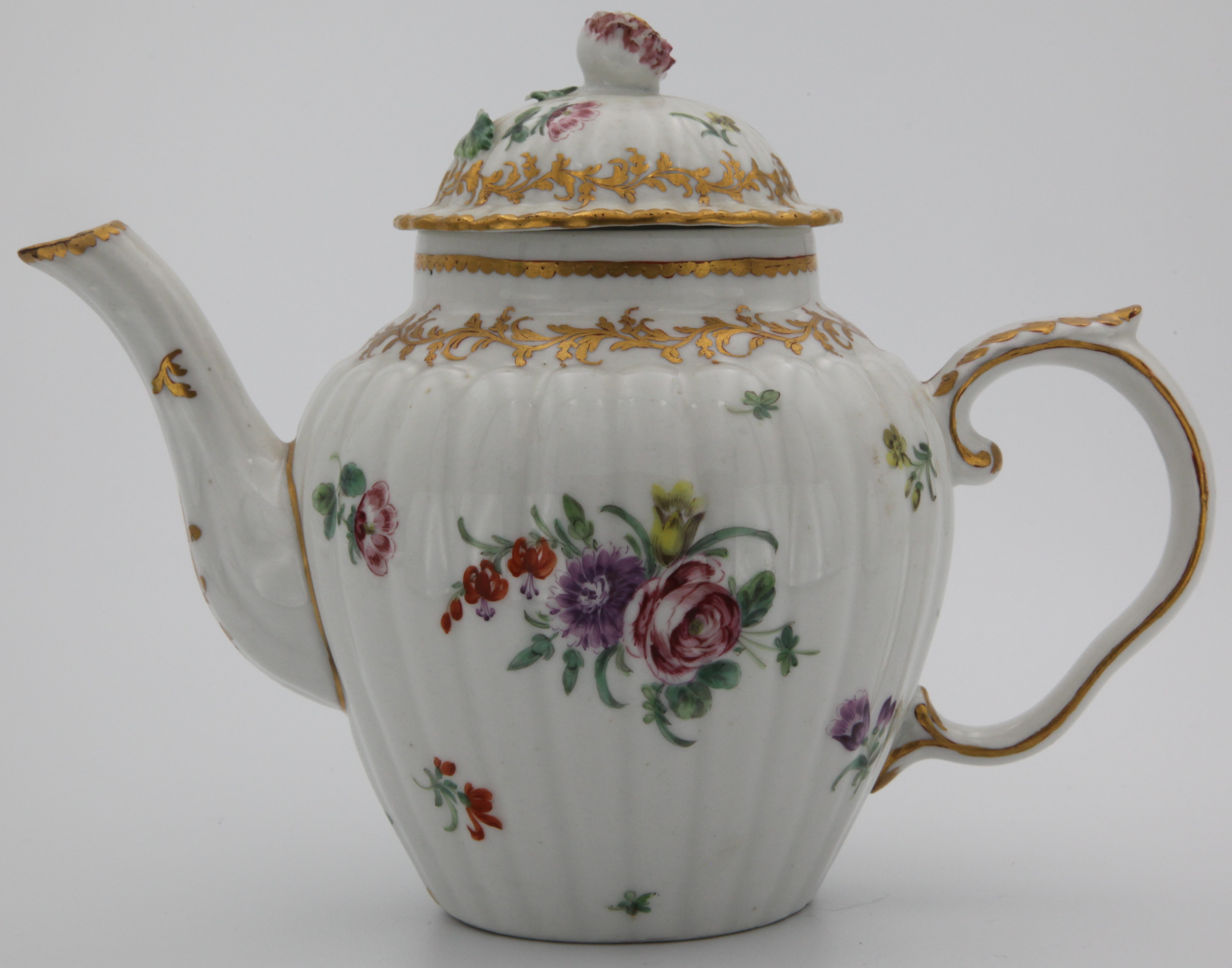 A fine Bristol teapot and cover, of fluted form, the shaped handle with a leaf thumbrest picked out in gold, the finial formed from a bud with closely-packed petals, painted in colourful enamels with floral sprays and scattered sprigs, an elaborate leafy gilt scrolled border below the gilt dentil rim, blue cross mark, gilded numeral 1.