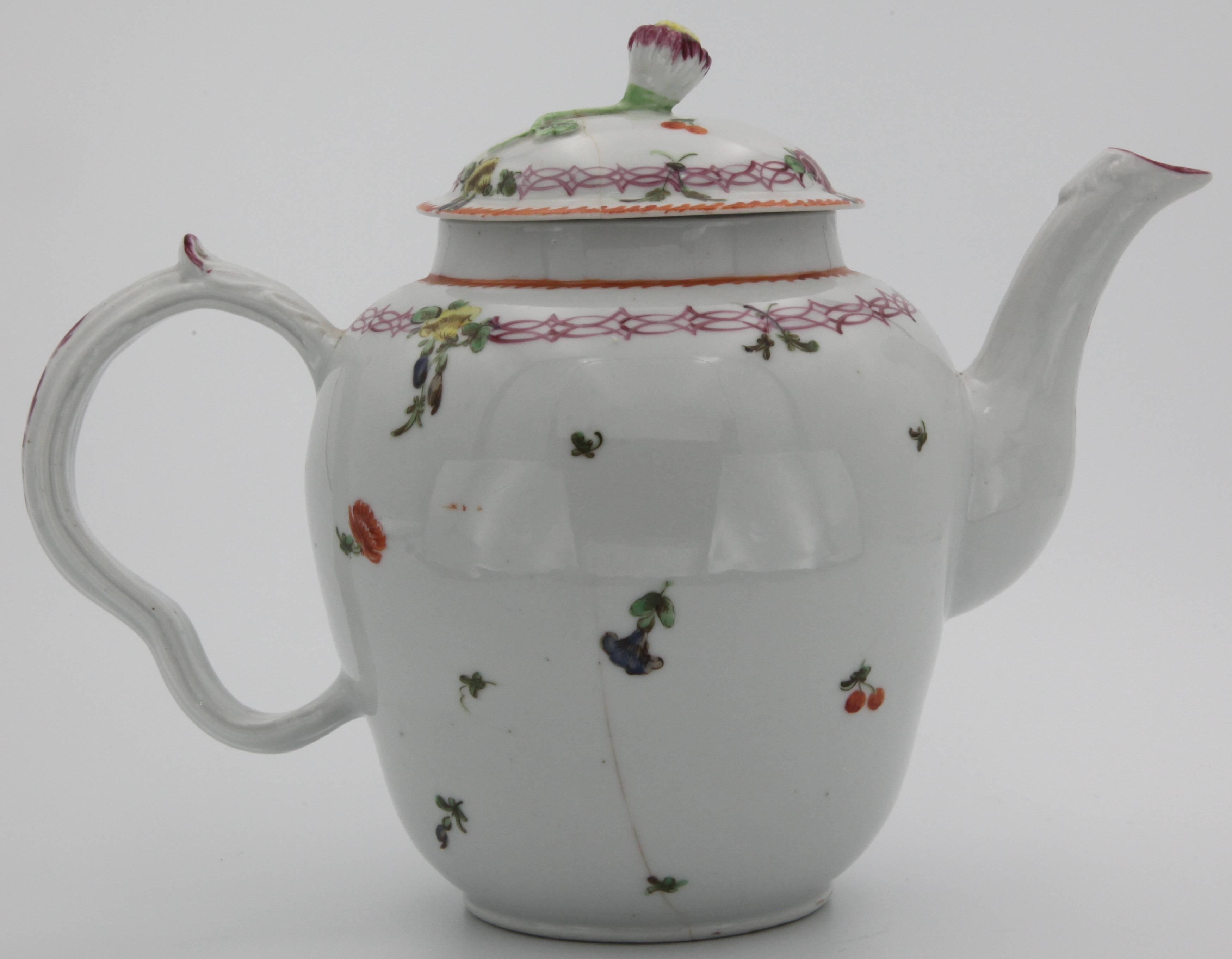 A Bristol teapot and cover with flower bud finial painted purple and yellow, with ear-shaped ridge-moulded handle with leaf thumbrest, highlighted in purple, the pot painted with scattered flowers, under a pink chain band suspending flowers and leaves, orange angular dentil rim. No mark