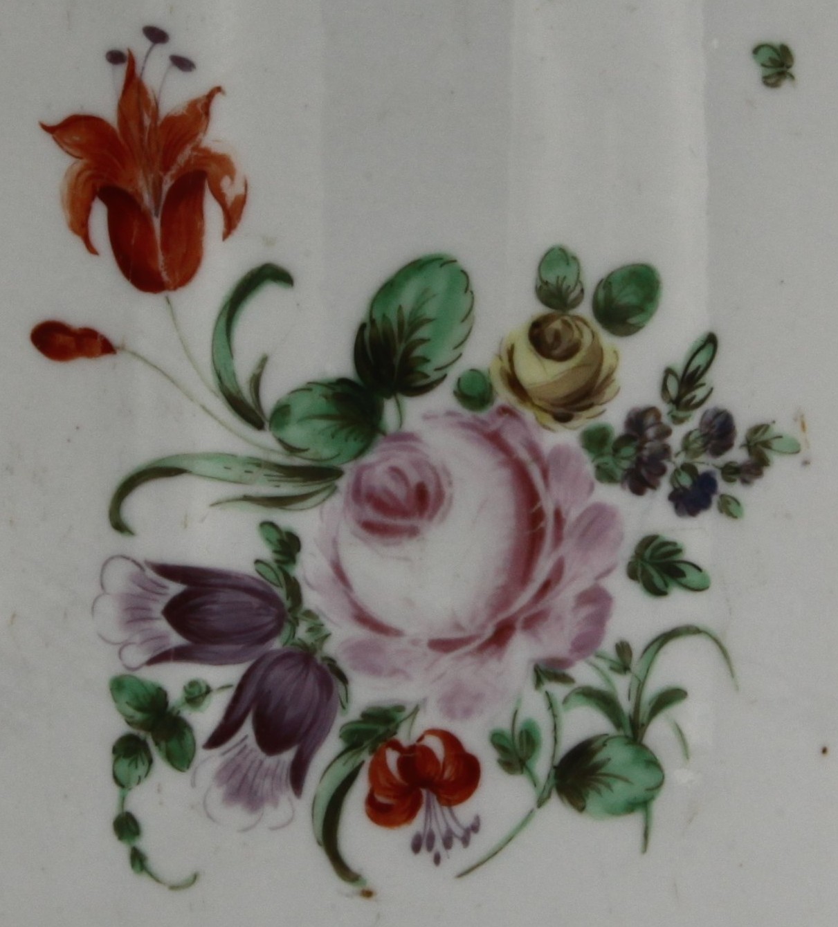 A large Bristol mug with simple undecorated ridged handle, painted in enamels with a spray of flowers to the front and scattered flowers and leaves, iron red rim, circa 1775. Mark X6.