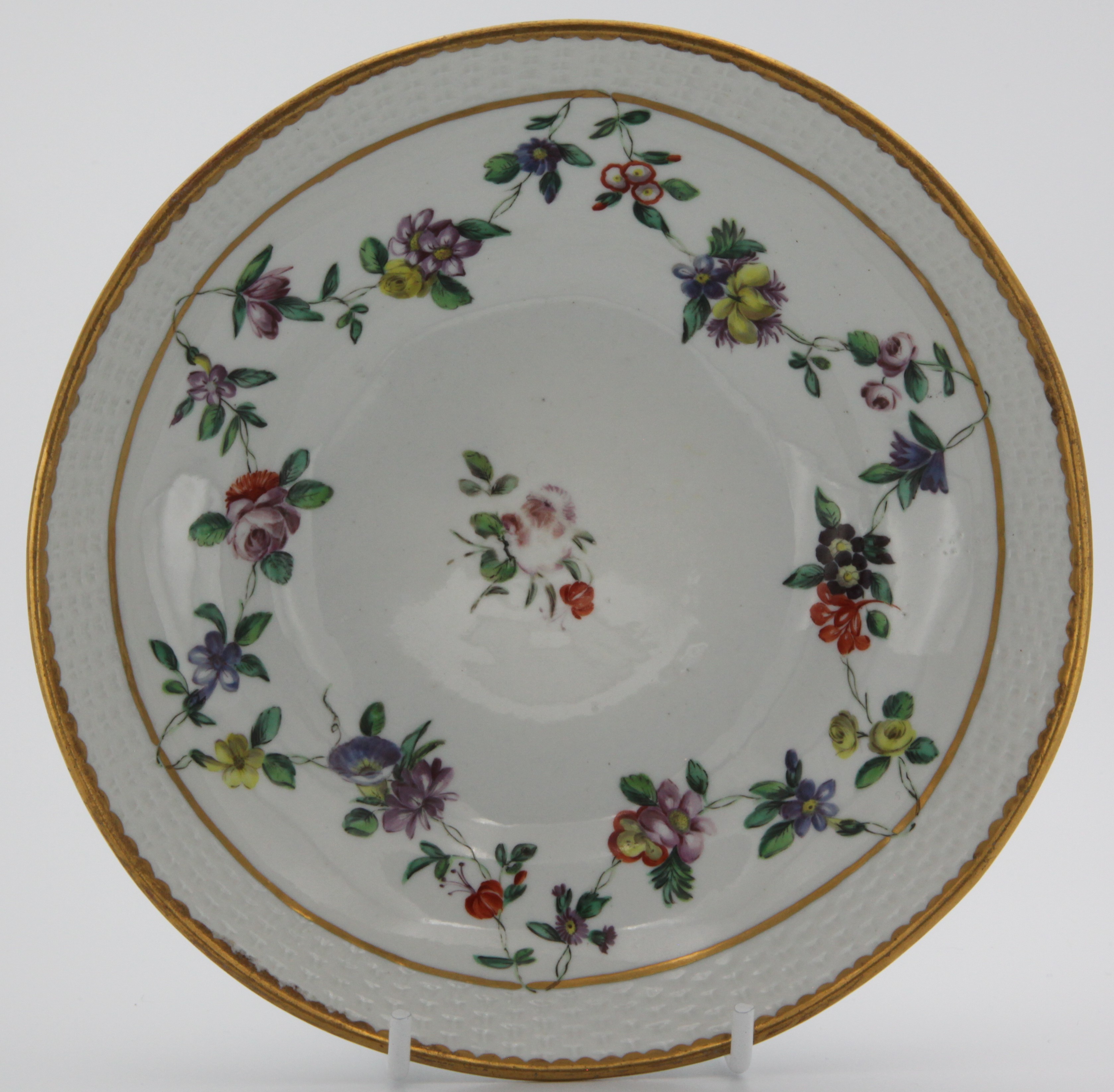 A large Bristol chocolate cup stand with upper basket-moulded band, painted in enamels with colouful floral festoons suspended from a gilt line, gilt dentil rim, blue X5 mark, circa 1775-80.
