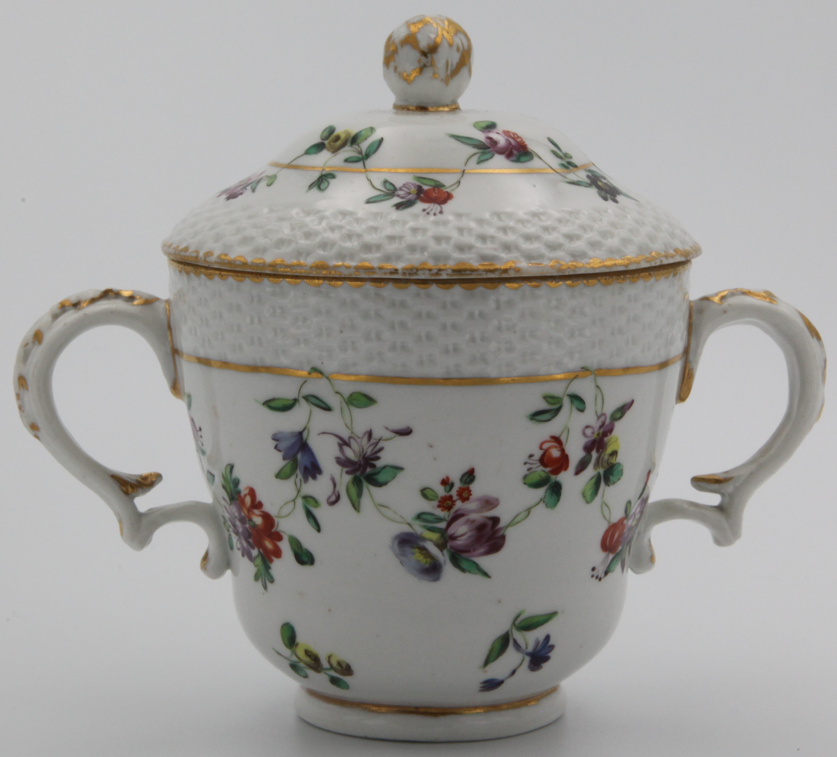 A Bristol chocolate cup and cover with bud finial and osier moulding, painted in enamels with colourful floral festoons suspended from a gilt line border surrounded by gilt dentil rim, blue X5 mark, circa 1775-80.