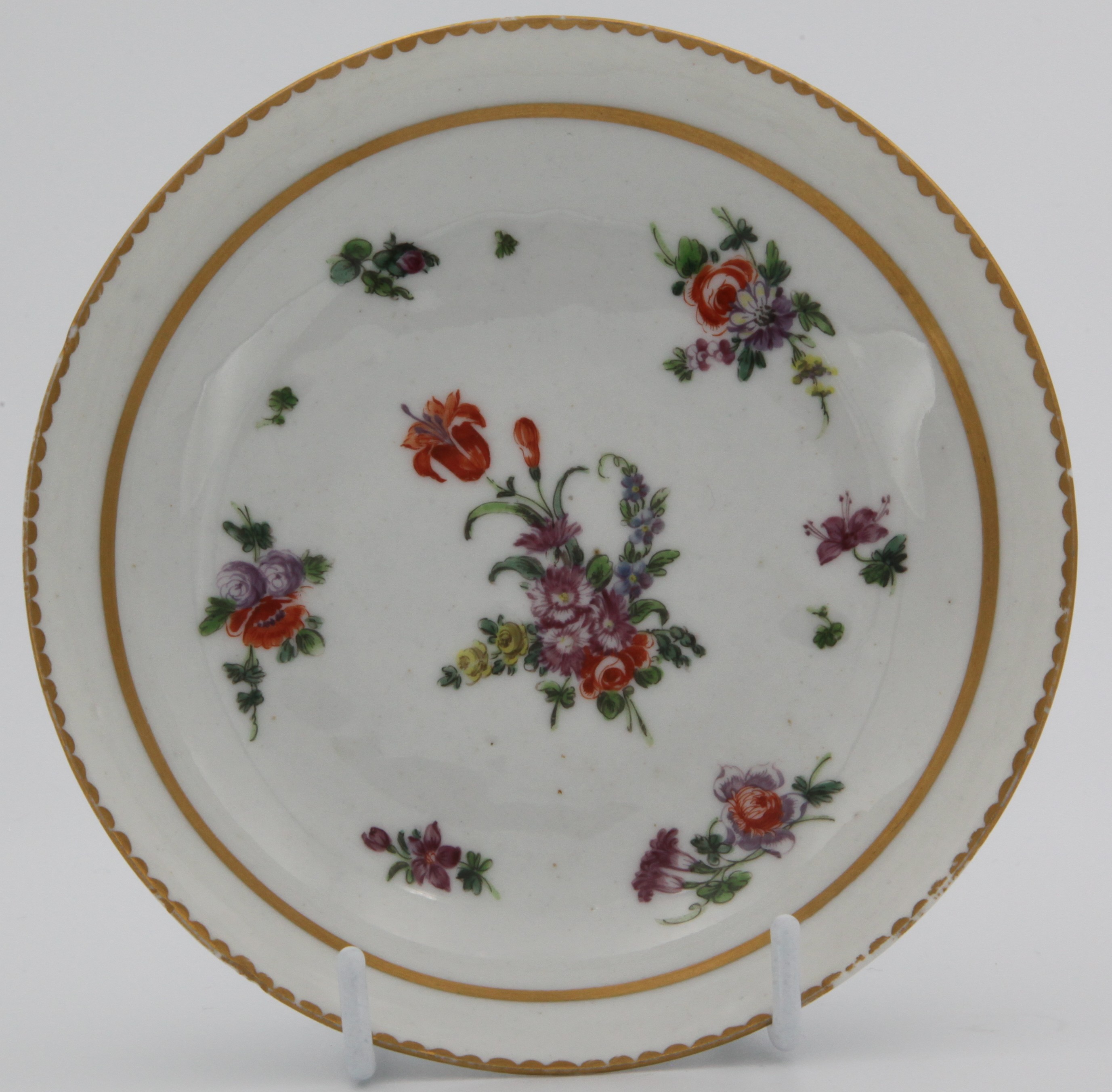 A Bristol coffee saucer painted with scattered flower sprays and sprigs with solid and dentil gilt borders, circa 1775-80. No mark.