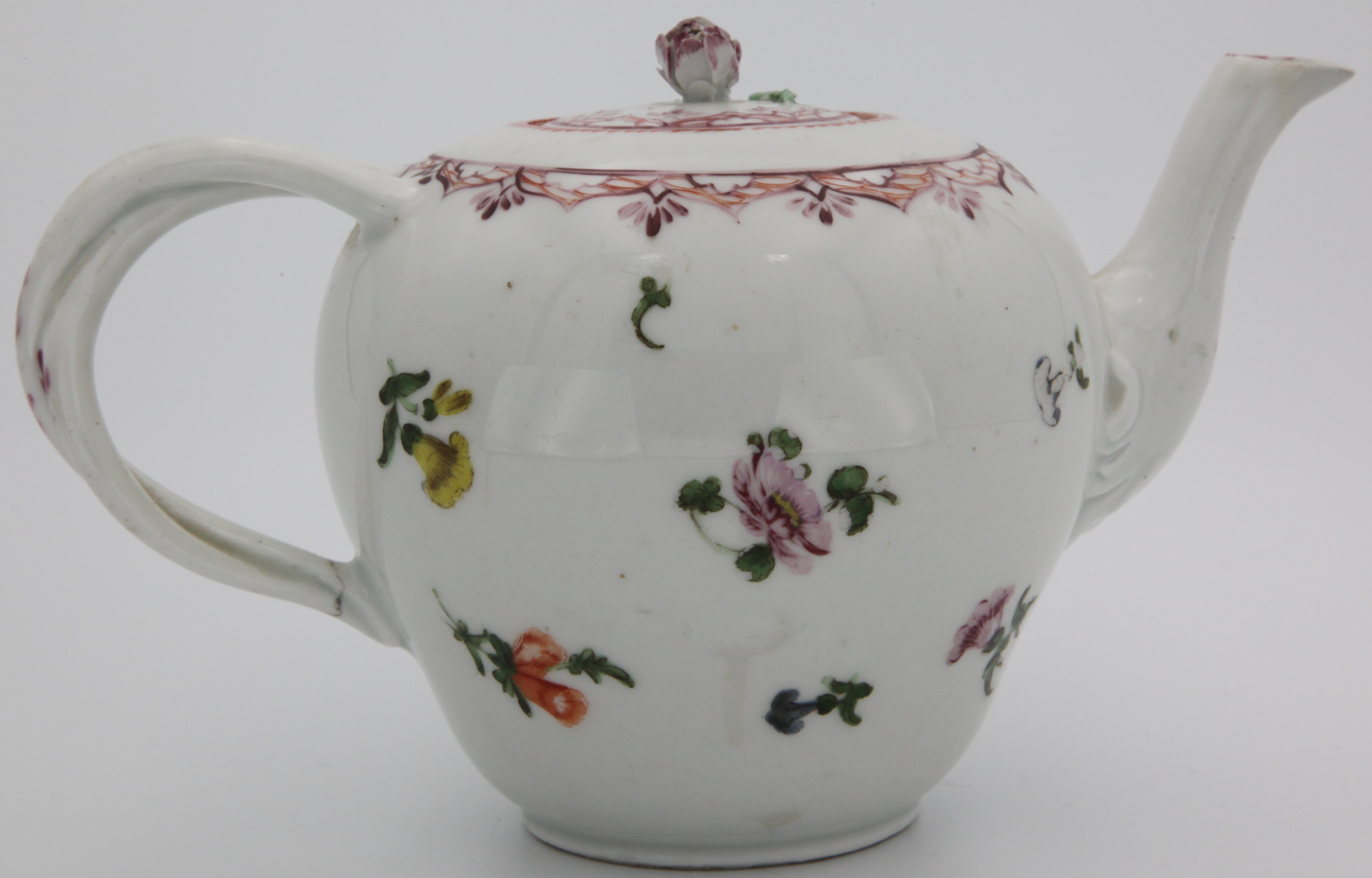 A Bristol teapot and cover of ogee form with entwined stalk handle, the cover with purple bud finial, painted with scattered sprigs and puce borders, orange dentil rim line circa 1775. No mark