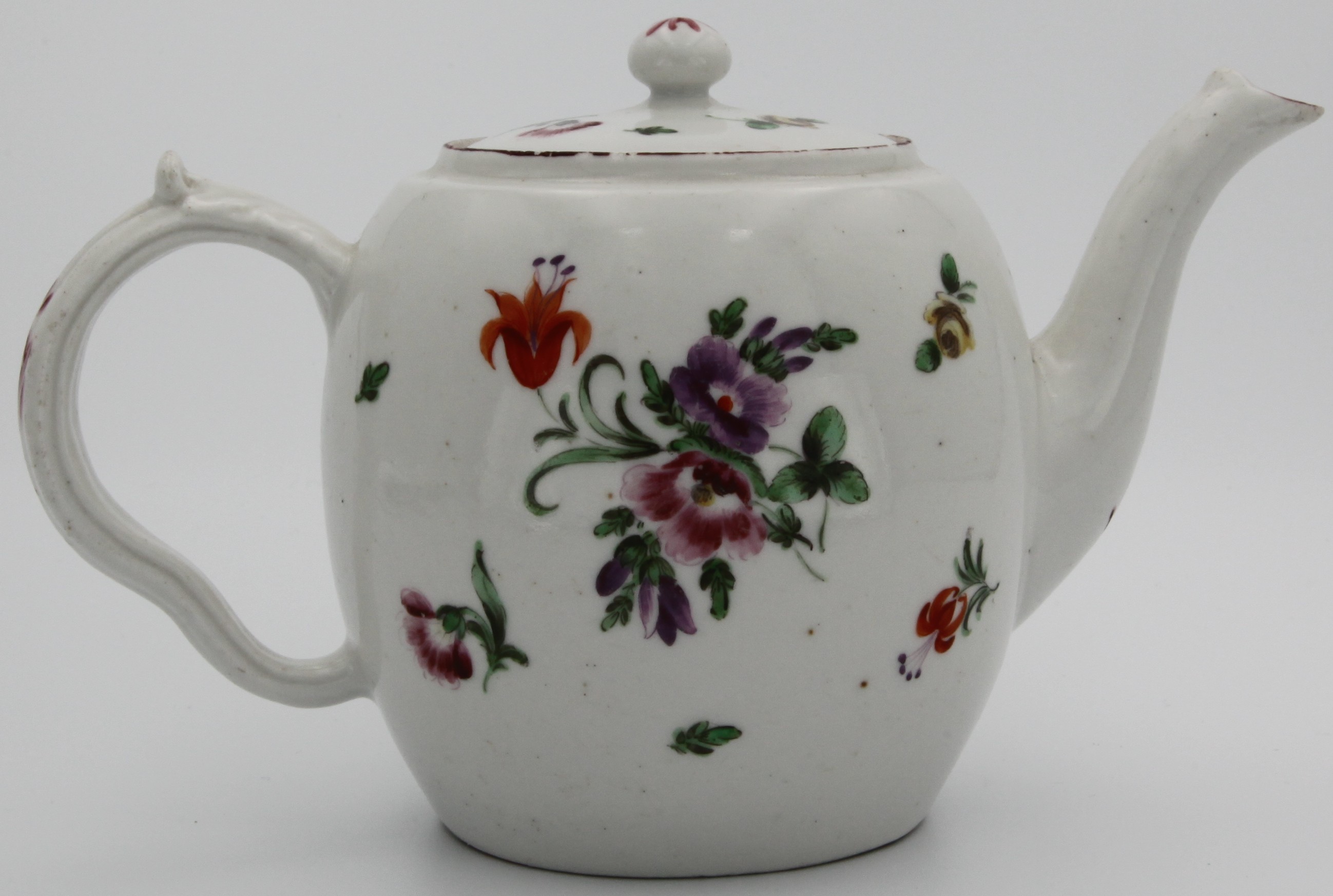 A small Bristol barrel-shaped teapot and cover with bun finial and ear-shaped handle moulded with acanthus scroll, painted with scattered flower sprays and sprigs, circa 1775. No mark