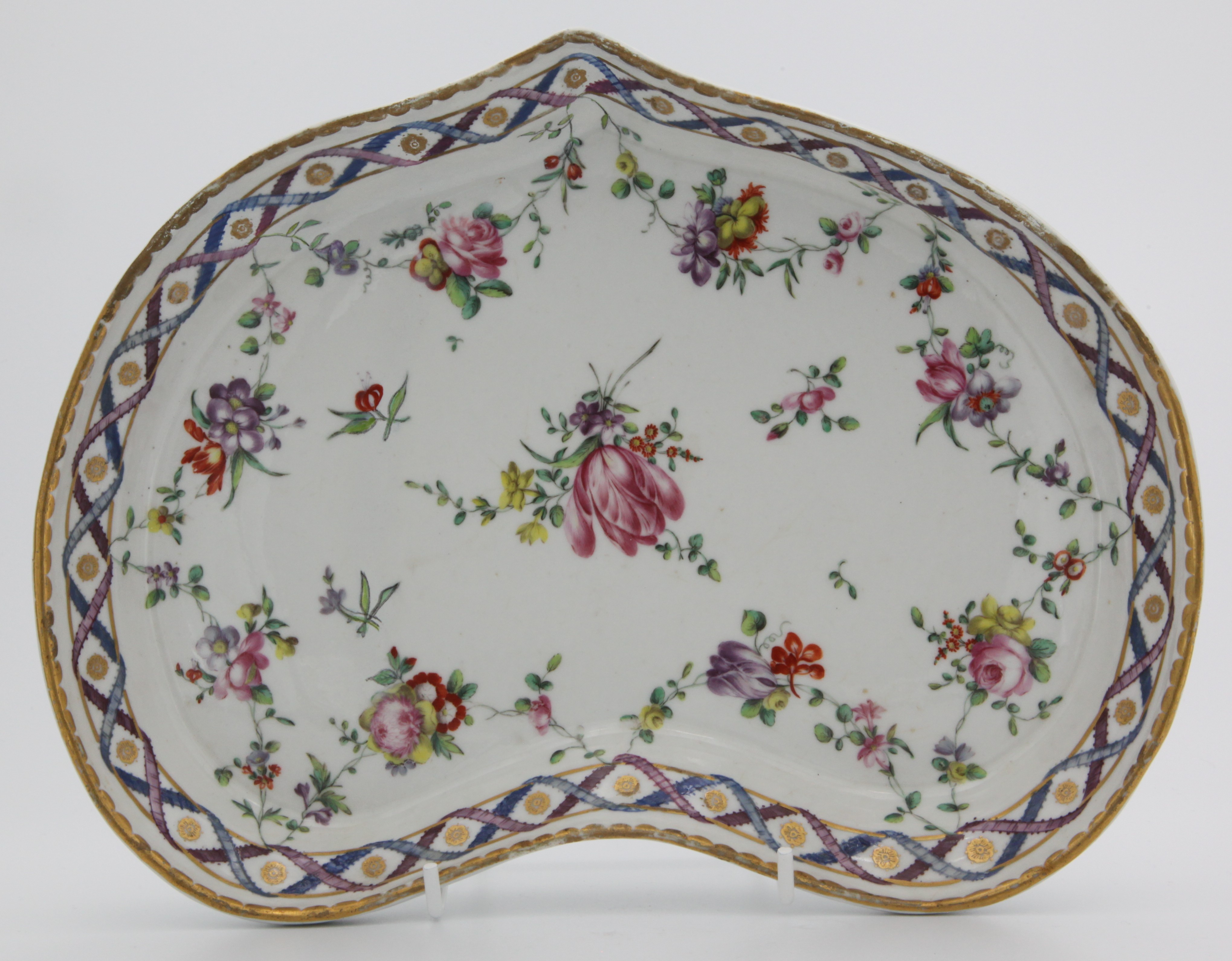 A Champion's Bristol heart-shaped dessert dish painted in the 'double ribbon' pattern of flower sprays and garlands suspended from entwined blue and puce ribbons, gilt dentil rim, blue X mark with 2 in gilt, circa 1775-80