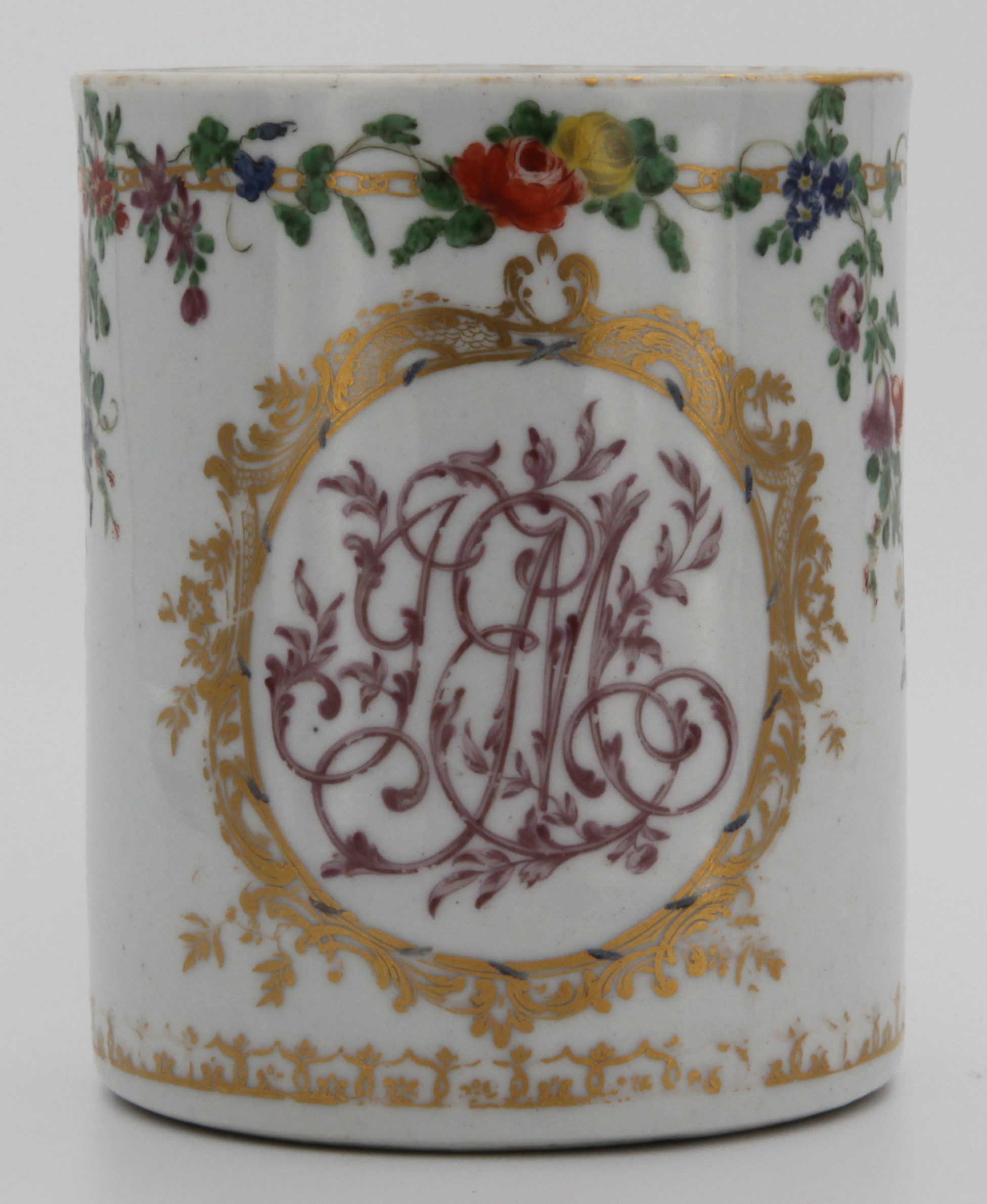A rare Bristol cylindrical mug, with notched loop handle, finely pianted in puce with the monogram 'JEM' and painted in coloured enamels with a band of flowers and leaves, suspending swags of flowers, circa 1770, tin mark in gilt.