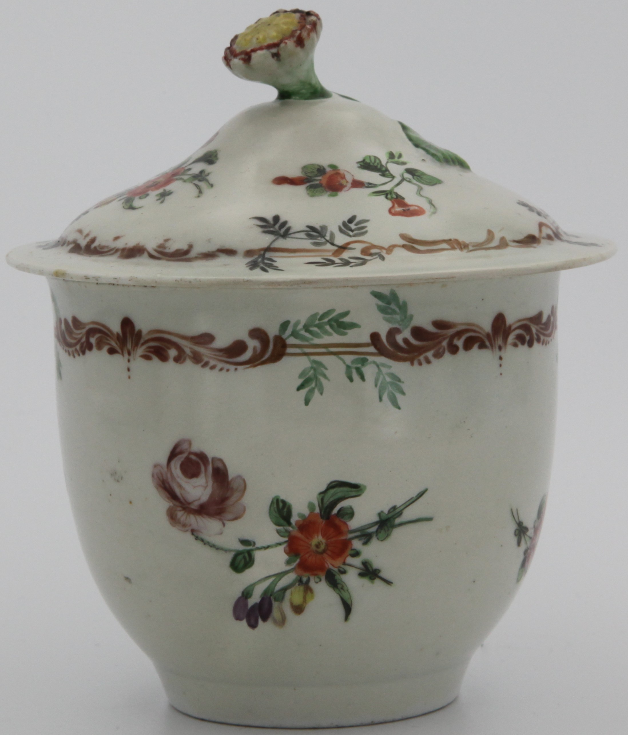 A Bristol sucrier and cover with bud finial painted in a number of layers with brown scroll band overpainting (except in one case underpainting) green fronds above sprays of flowers painted in enamels, no mark