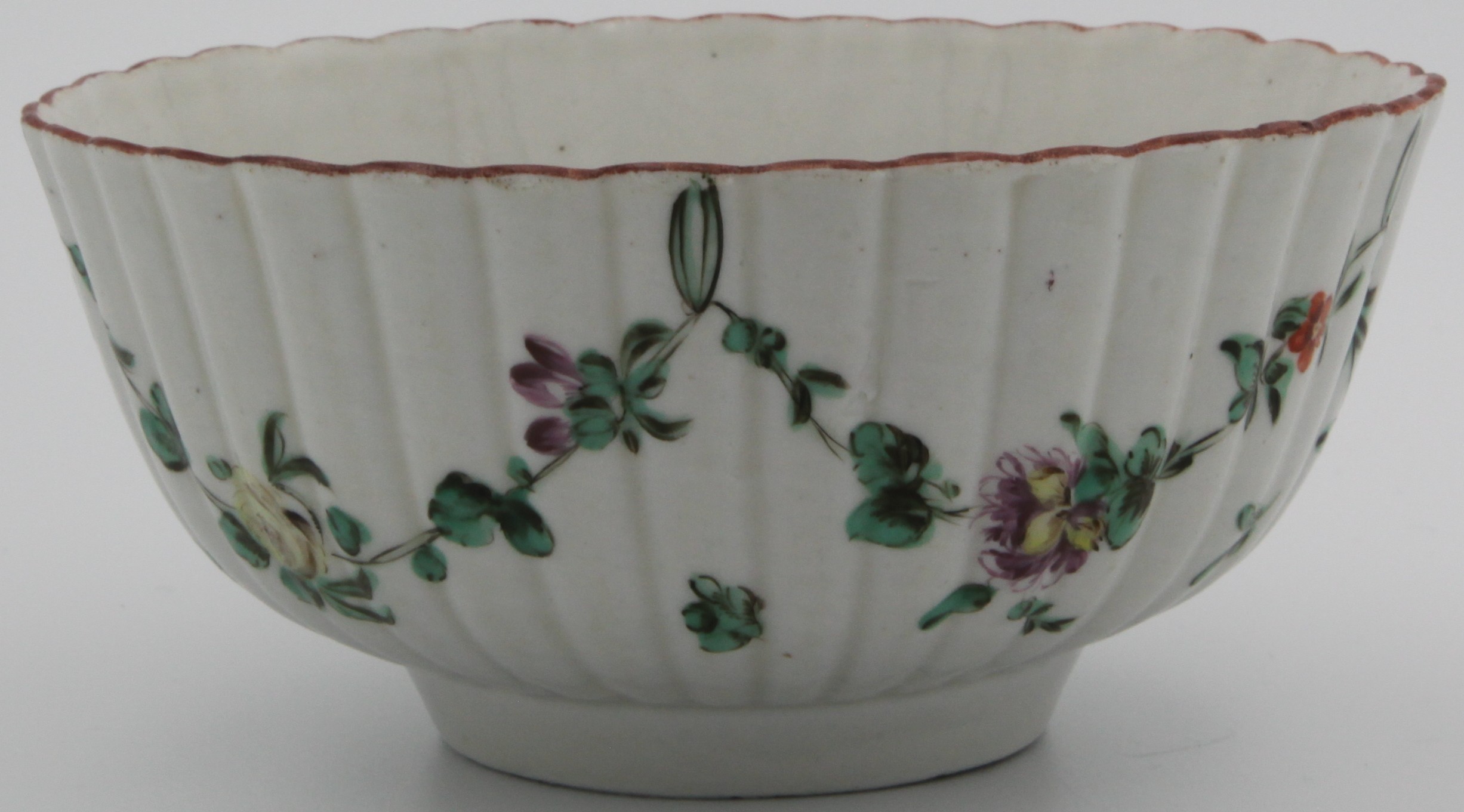 A Bristol porcelain floral slop bowl. Fluted bowl decorated with largely green garlands suspended from green loops hanging from iron red rim, 14cm wide, grey X16 mark