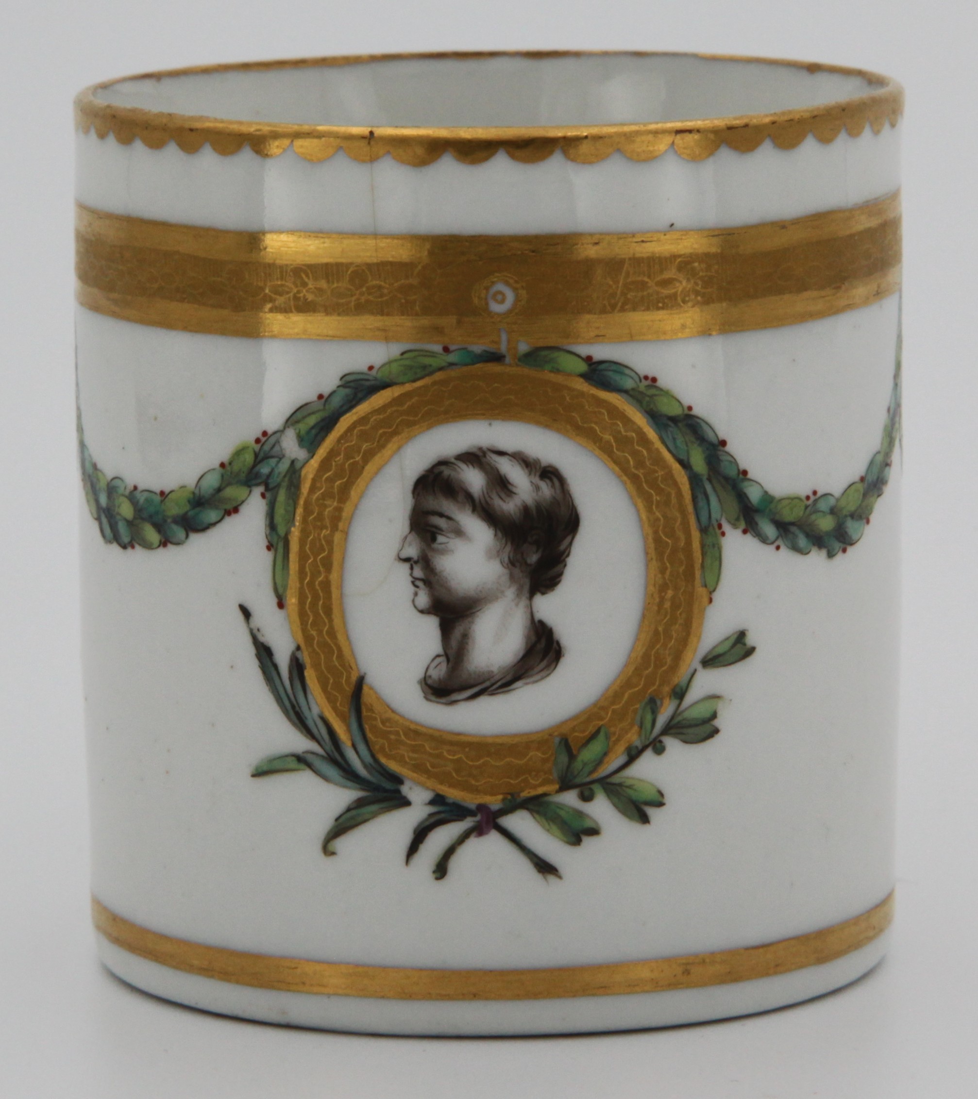 A rare Bristol coffee can, with harebell-moulded ear-shaped handle, painted en grisaille with a male profile, within a tooled gilt oval panel, above laurel and suspended from looped laurel swags, beneath a tooled gilt band, gilt dentil rim,  circa 1775, no mark.