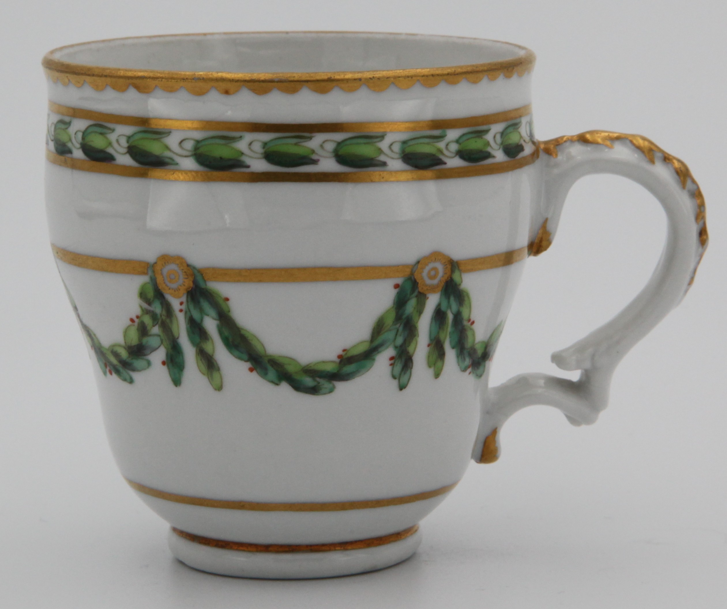 A Bristol ogee-shaped coffee cup, with harebell-moulded ear-shaped handle, painted in green and iron red with laurel swags, suspended from gilt bands within green leaf scroll bands and gilt dentil rims, circa 1775. Blue X mark