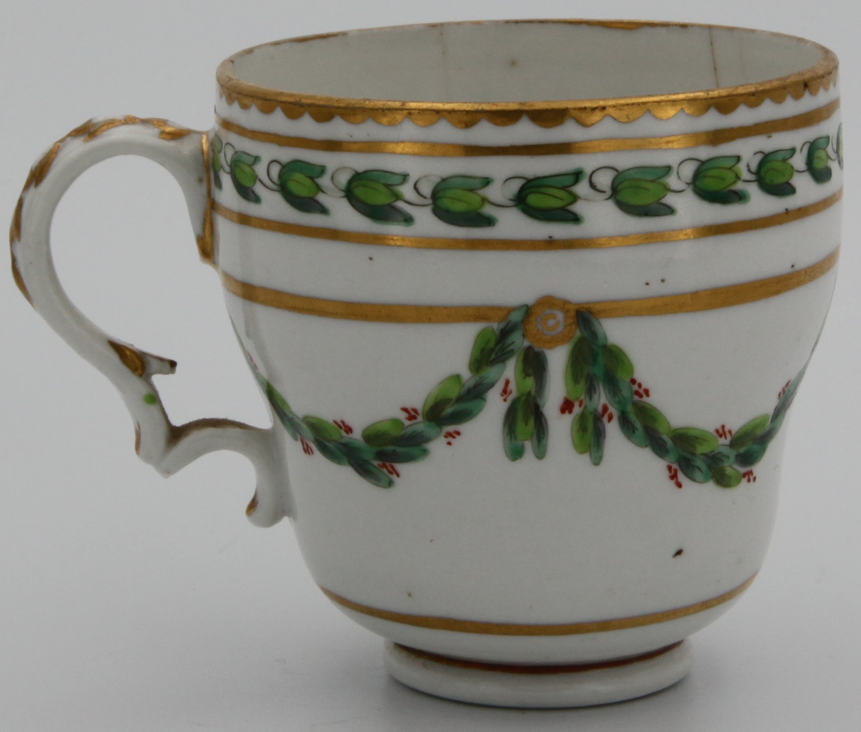 A Bristol ogee-shaped coffee cup, with harebell-moulded ear-shaped handle, painted in green and iron red with laurel swags, suspended from gilt bands within green leaf scroll bands and gilt dentil rims, circa 1775. Blue X1 mark