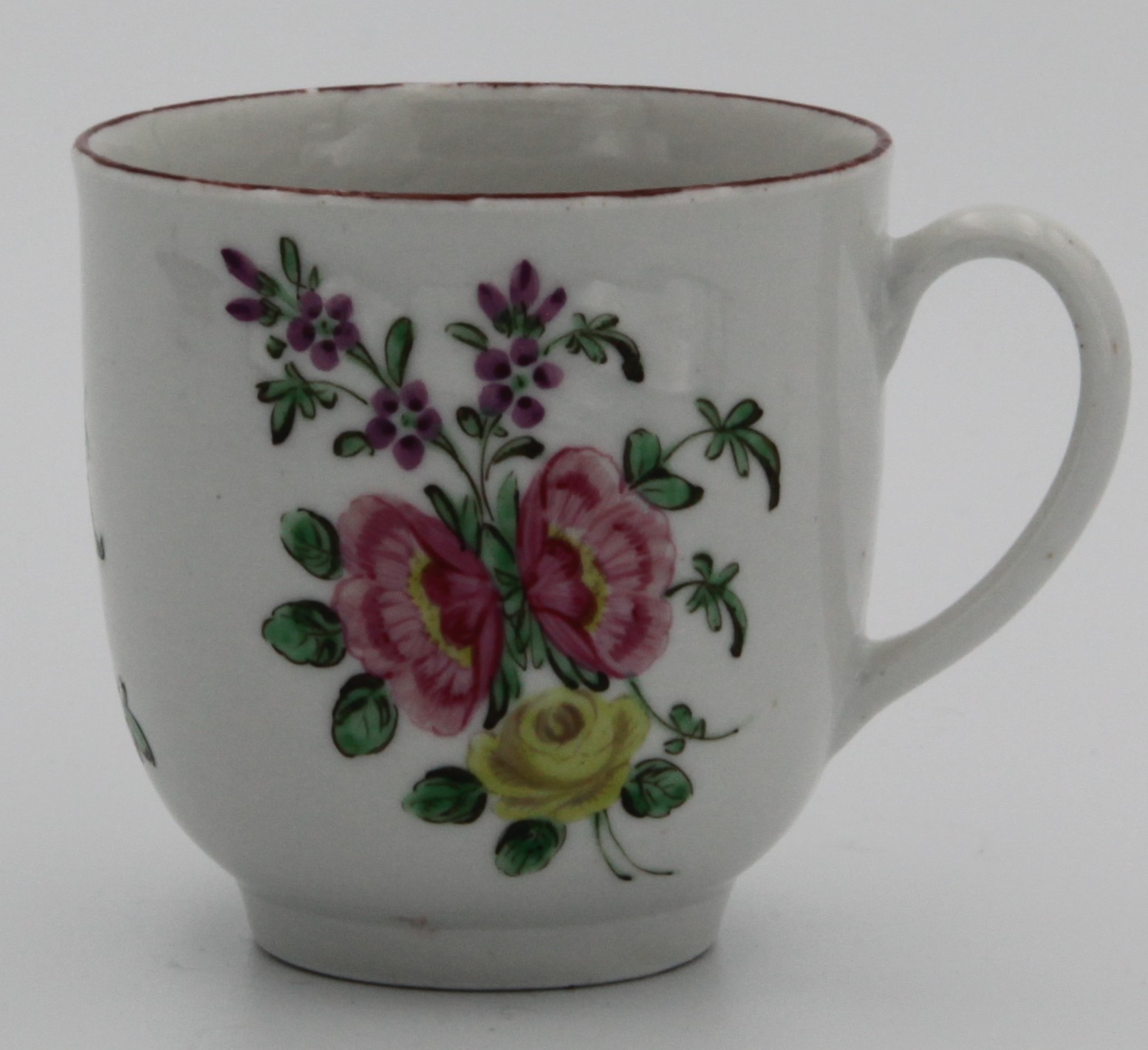 A Bristol coffee cup, circa 1775. Painted with a spray of two pink and one yellow flowers, the reverse with scattered flowers, and an iron red line rim. Marked with numeral 7. in blue to base.