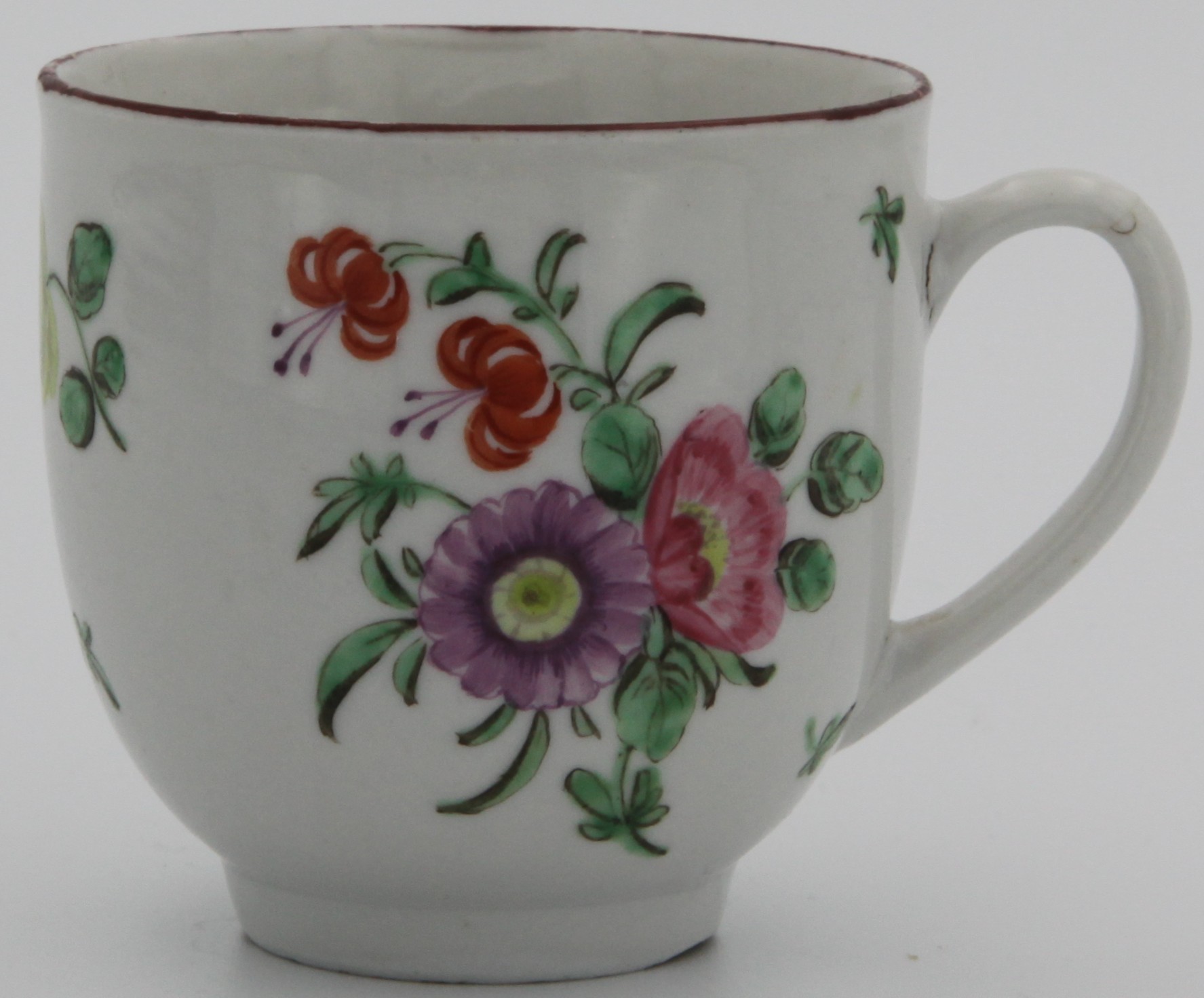 A Bristol coffee cup with plain handle, painted with a spray of purple, pink and two orange flowers, the reverse with scattered flowers and leaves, and an iron red line rim. Marked with blue X and numeral 7. painted in blue to base. Circa 1775