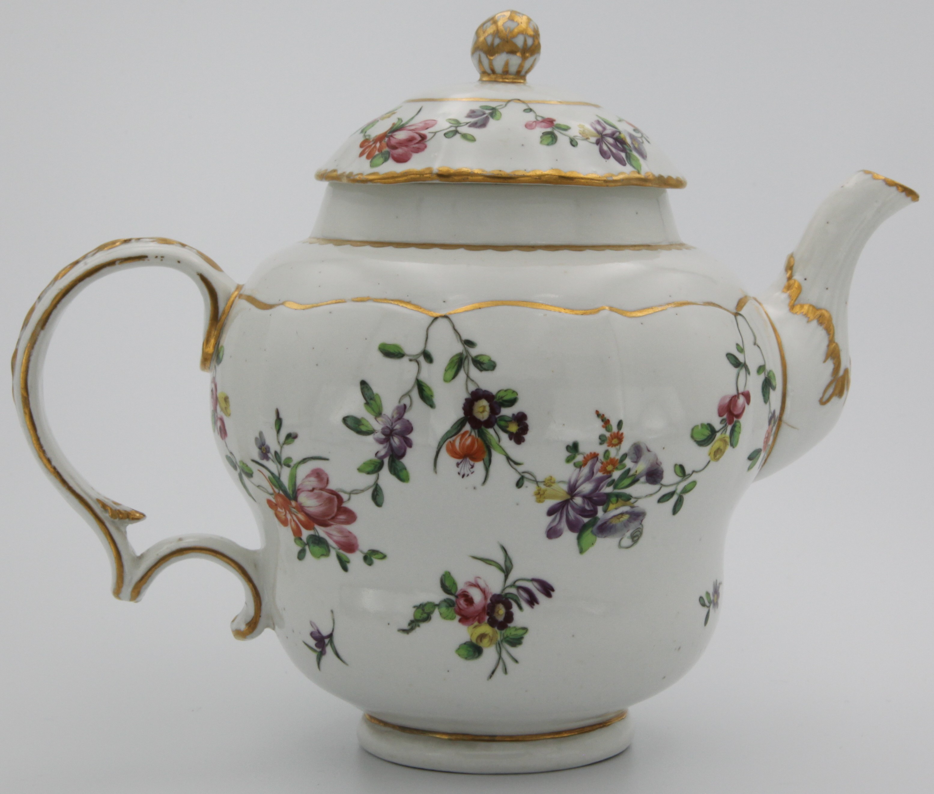 A large ogee-shaped Bristol teapot and cover with gilt painted knop, the handle harebell-moulded and gilt painted, with garlands of flowers suspended from gilt lines, gilt dentil trim, 17cm high. Blue X mark