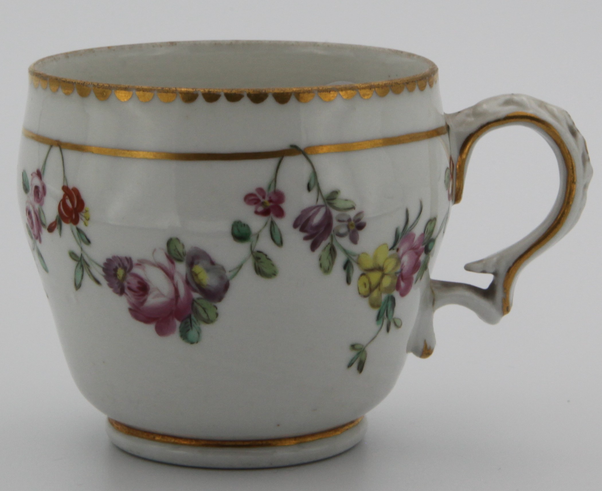 An ogee-shaped Bristol coffee cup with harebell moulded shaped handle, painted in enamels with garlands of colourful flowers suspended from gilt line, with gilt dentil rim, Xb mark