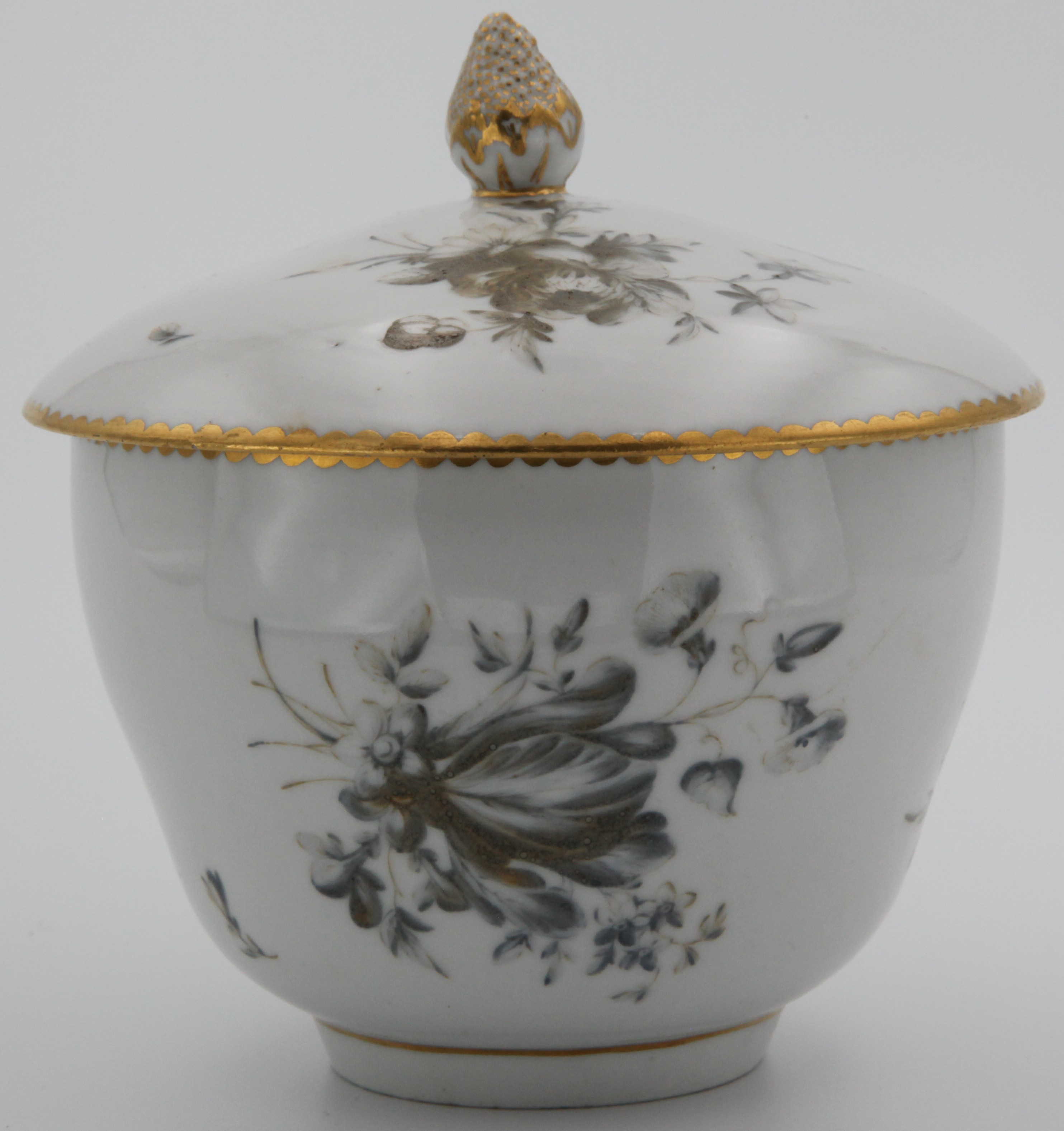 A rare Bristol ogee-shaped sucrier and cover, from the Fry service, with pinecone knop, painted in delicate pale "dry blue" enamel by William Stephens with flower sprays and scattered flowers, gilt dentil borders, circa 1775, blue painted X mark and numeral 2 in gilt.  See FS Mackenna, Plymouth and Bristol Porcelain, number 96, for the cream jug from this service, probably made for Joseph Fry, Quaker friend and financial backer of Champion. A tea cup from this serrvice was in the Peter Stephens collection
