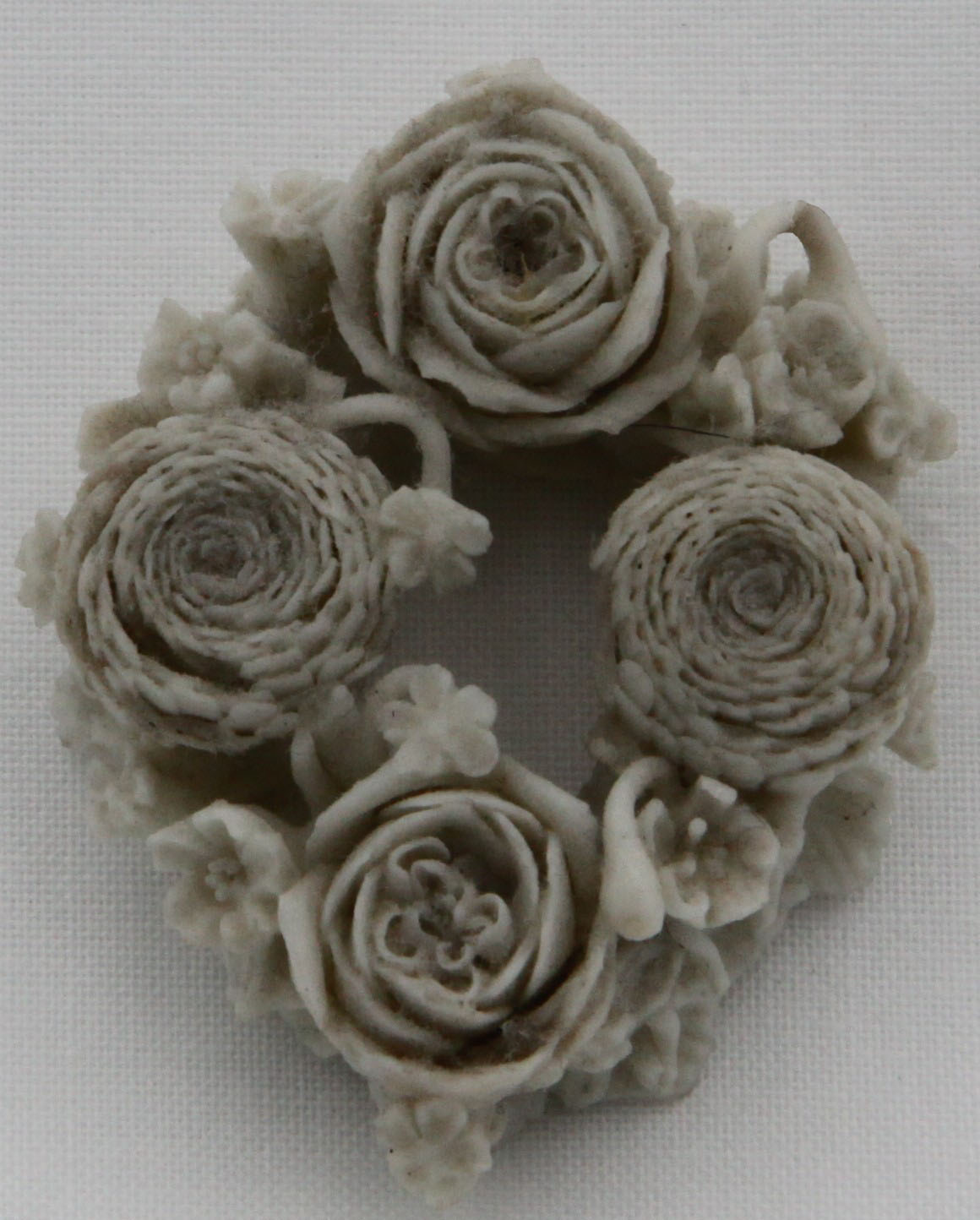 A  Bristol white biscuit porcelain floral brooch circa 1775 modelled as a circular wreath of tightly coiled roses and smaller flowers