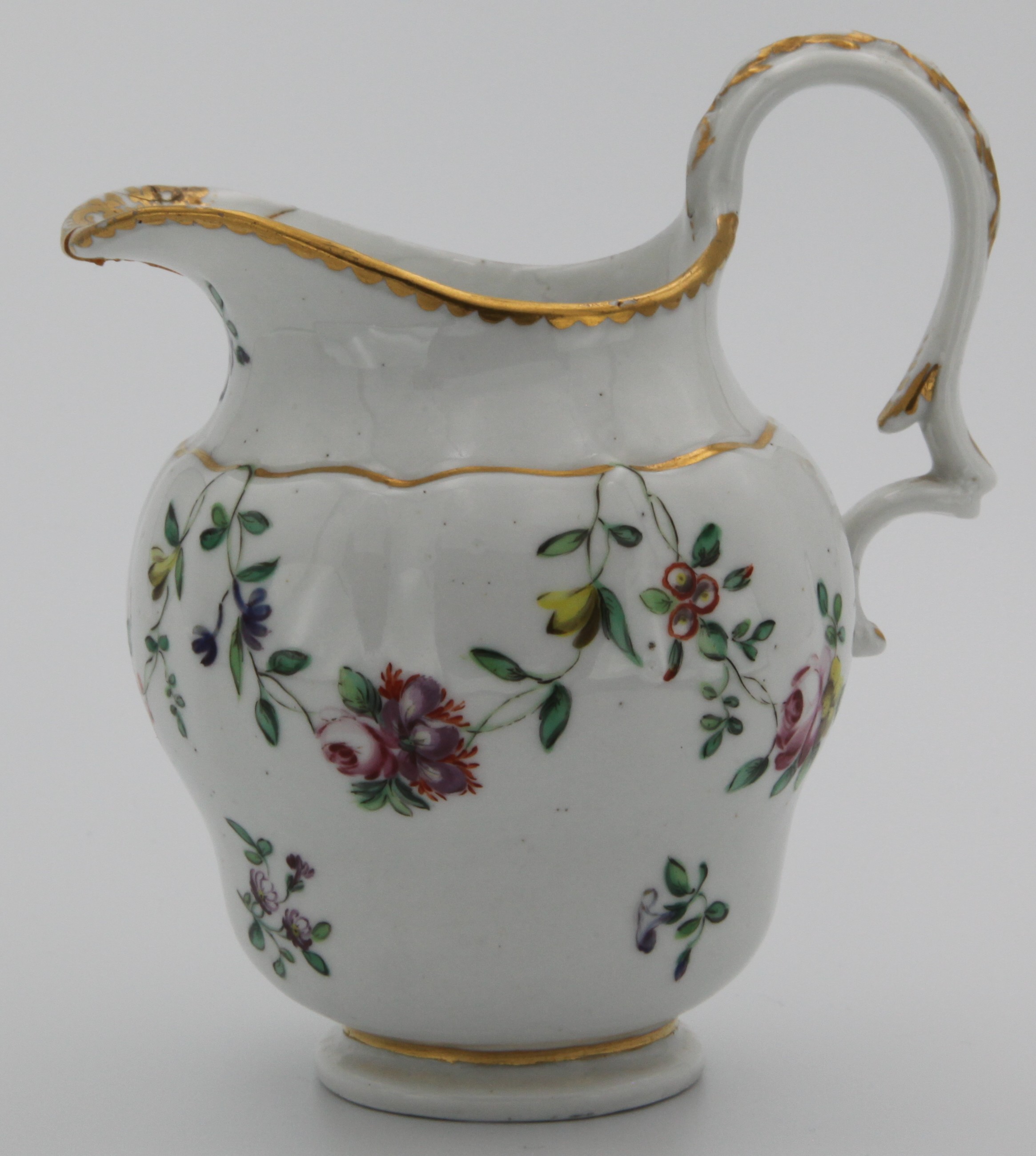 A Bristol milk jug painted in coloured enamels with swags of flowers and leaves, suspended from gilt bands, within gilt dentil borders. Blue X5 mark.