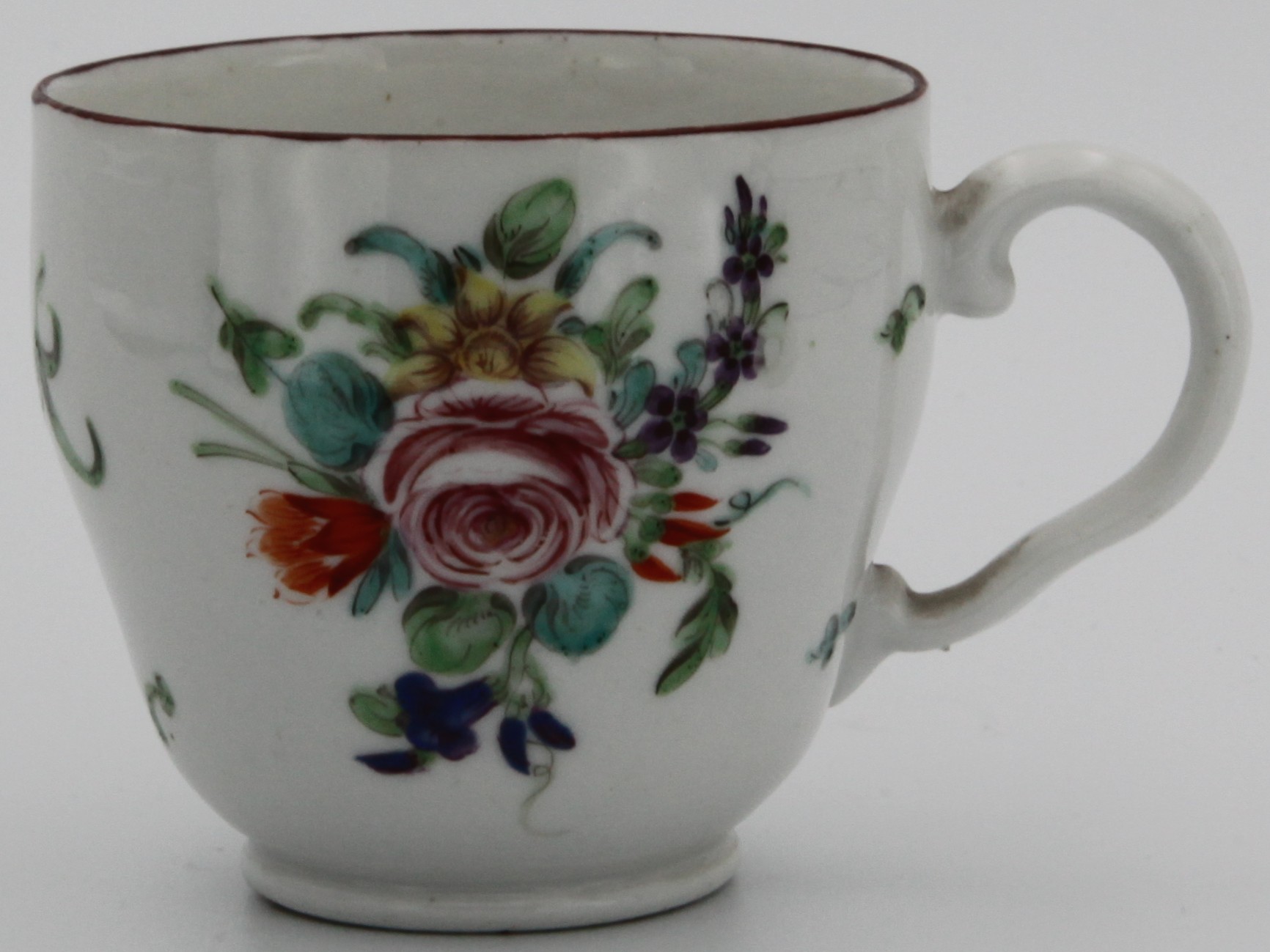 Bristol coffee cup of ogee form and with ear-shaped handle,  painted with spray of flowers with central rose and scattered flowers and leaves with iron red rim c. 1775-78. Mark: underglaze blue crossed swords with dot and painted blue X.