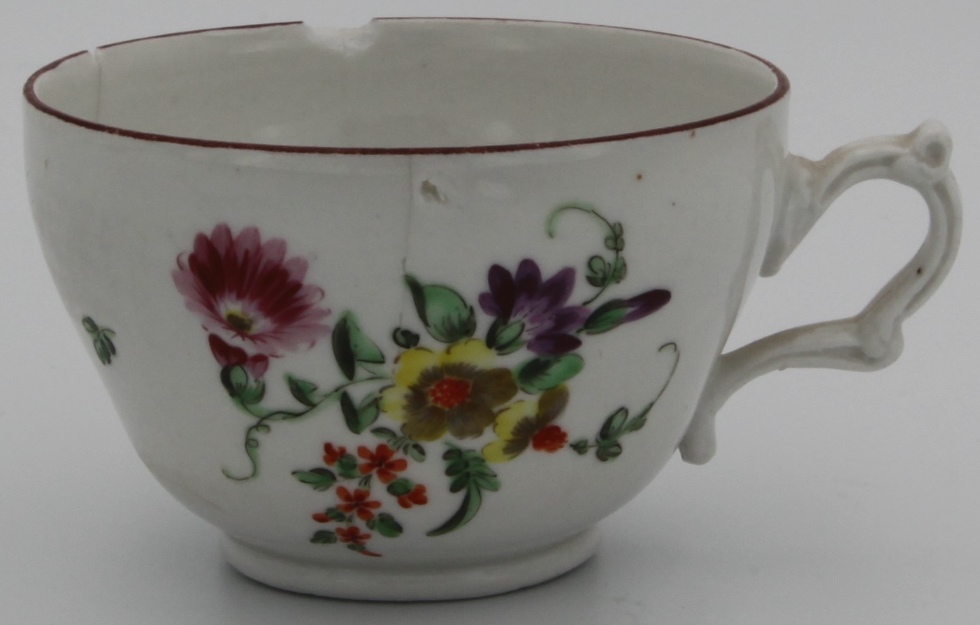 A Bristol tea cup, circa 1775. Painted with a spray of flowers, the reverse with scattered flowers, and an iron red line rim.