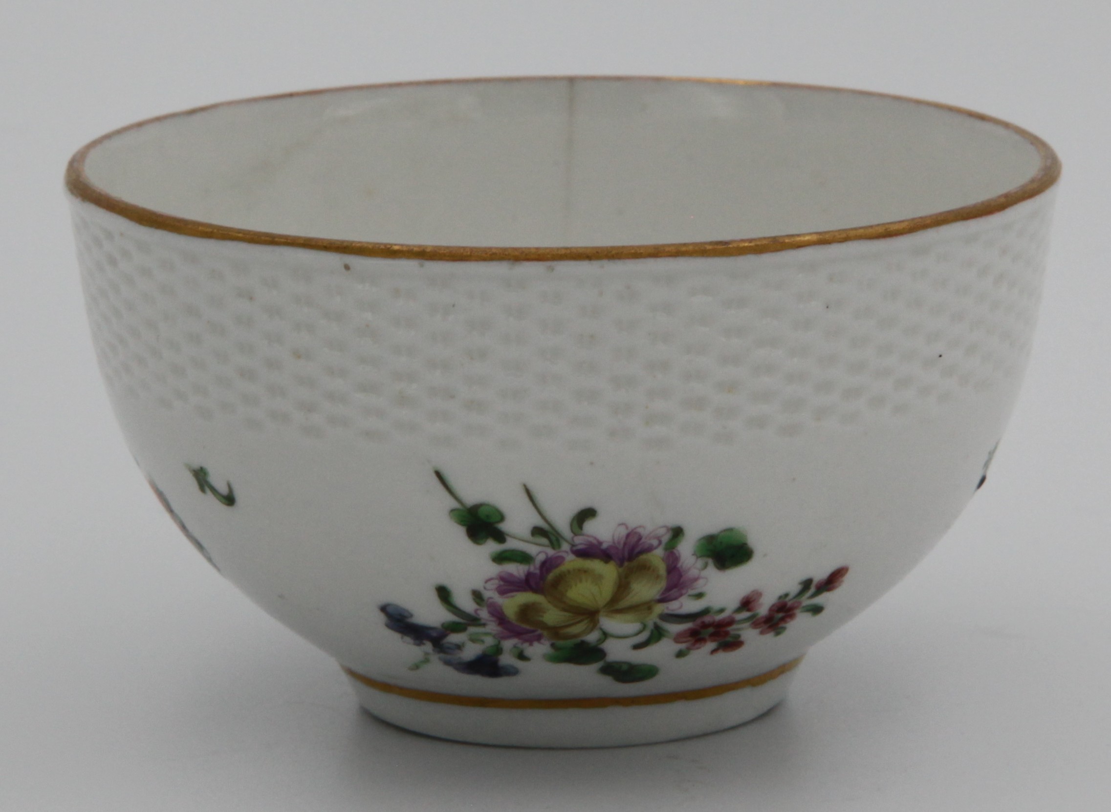 A small Bristol bowl, the upper third with basket moulding, painted with colourful enamel spray and loose flowers and leaves between simple gilt rim and lower gilt line around base, blue X mark