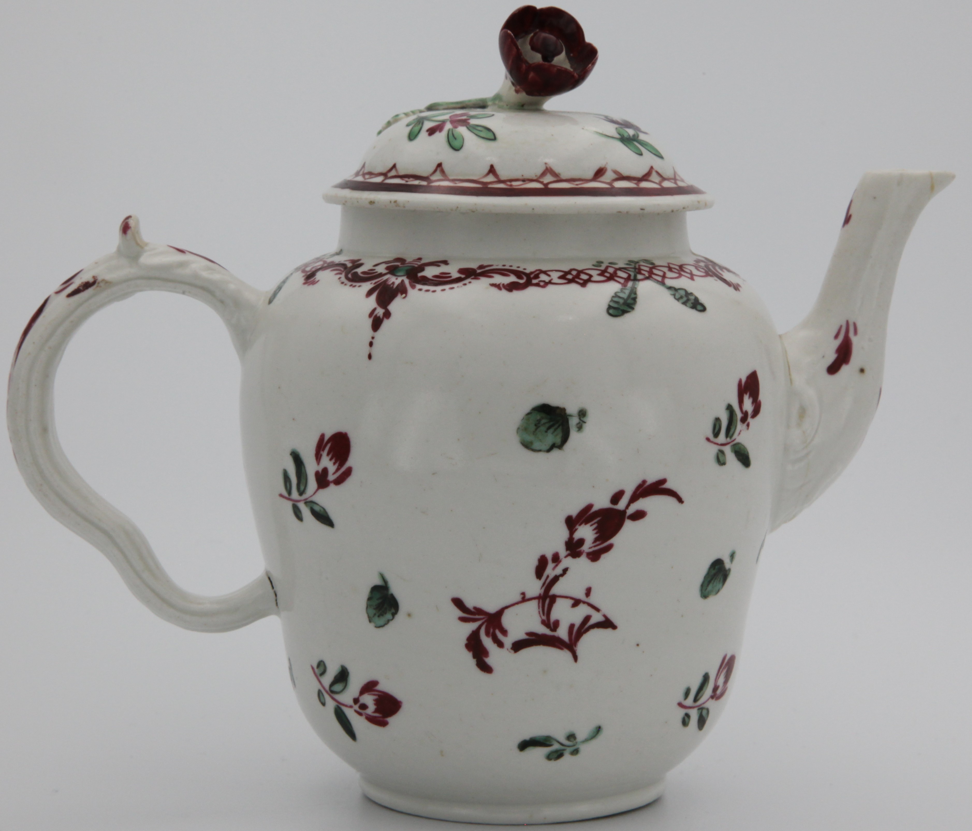 A Bristol teapot and cover, c.1772-75, the ogee form painted with scattered flower sprays in red and green beneath a formal border. Faint blue X mark obscured by brown paint. 10cm high.