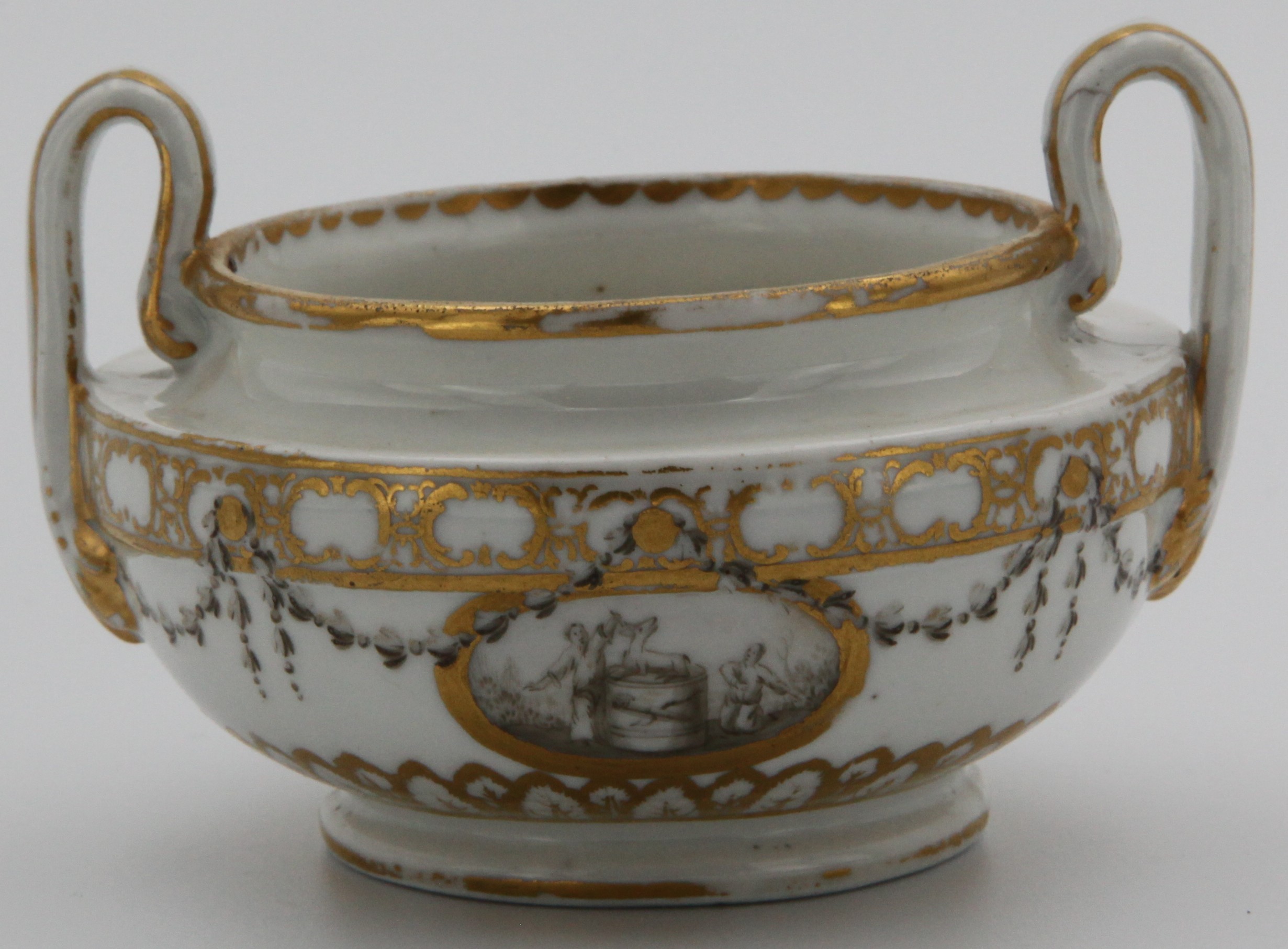 One of a rare pair of Bristol porcelain two-handled pots or vases, c.1772-75, the squat Etruscan forms painted with en grisaille panels of figures flanking garden statuary and hearts, within monochrome husk garlands and formal gilt borders, blue X marks. This pair decorates the title page of Hugh Owen's Two Centuries of Ceramic Art in Bristol.