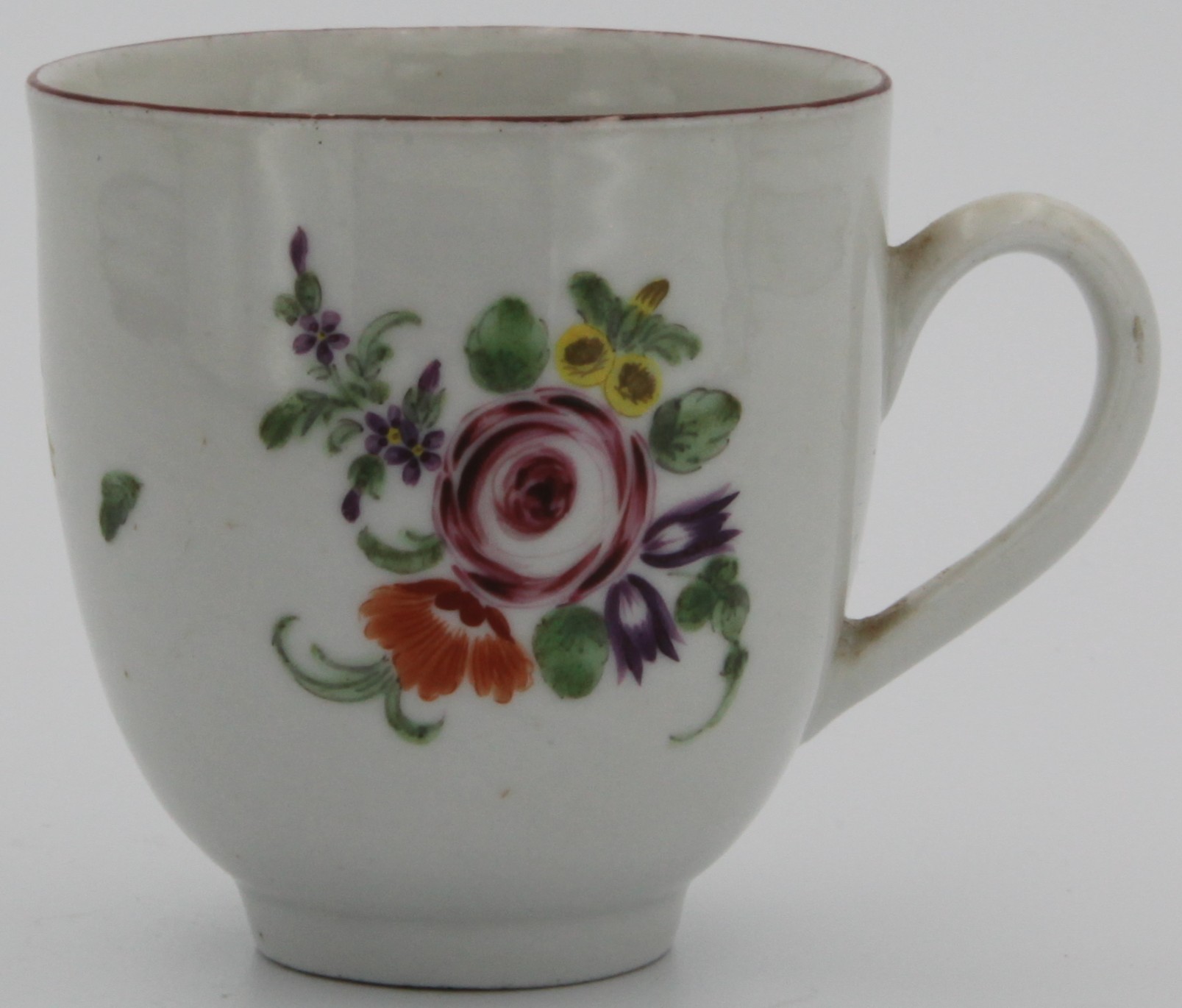 A Bristol coffee cup with plain handle, painted with a spray of flowers around a rose and scattered flowers and leaves under a brown line rim c. 1773-75. No mark