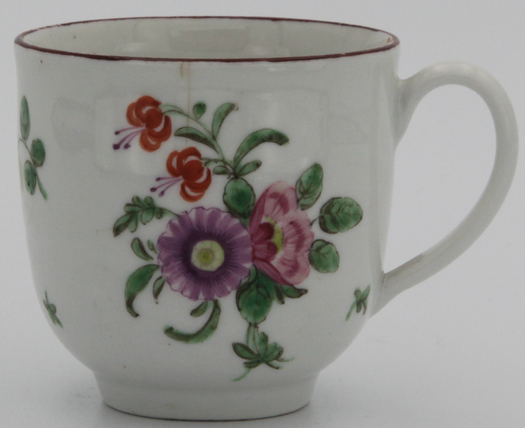 A Bristol coffee cup with plain handle, painted with a spray of purple, pink and two orange flowers, the reverse with scattered flowers and leaves, and an iron red line rim. Marked with blue X and numeral 7. painted in blue to base. Circa 1775