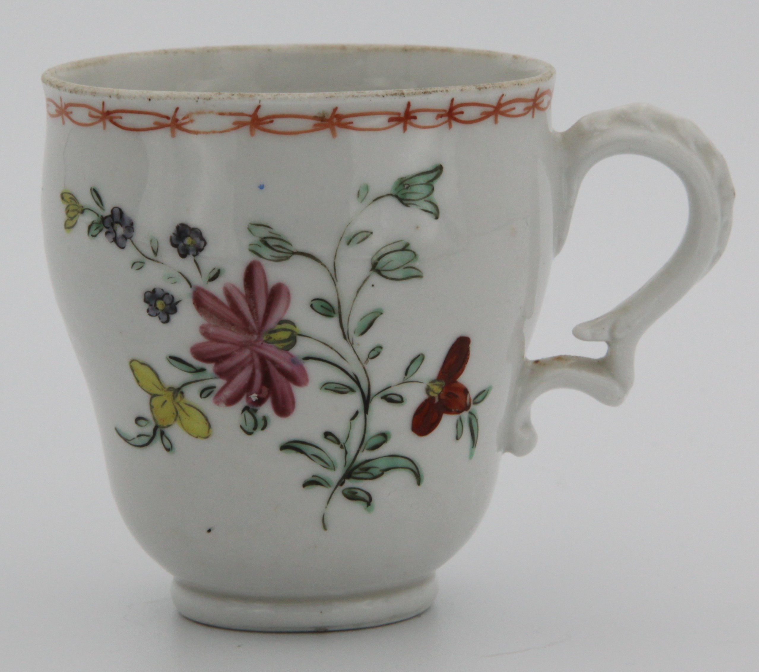 A Bristol coffee cup with harebell moulded handle, painted simply with wild flower under an orange chain border c. 1775-78.  Mark: none.