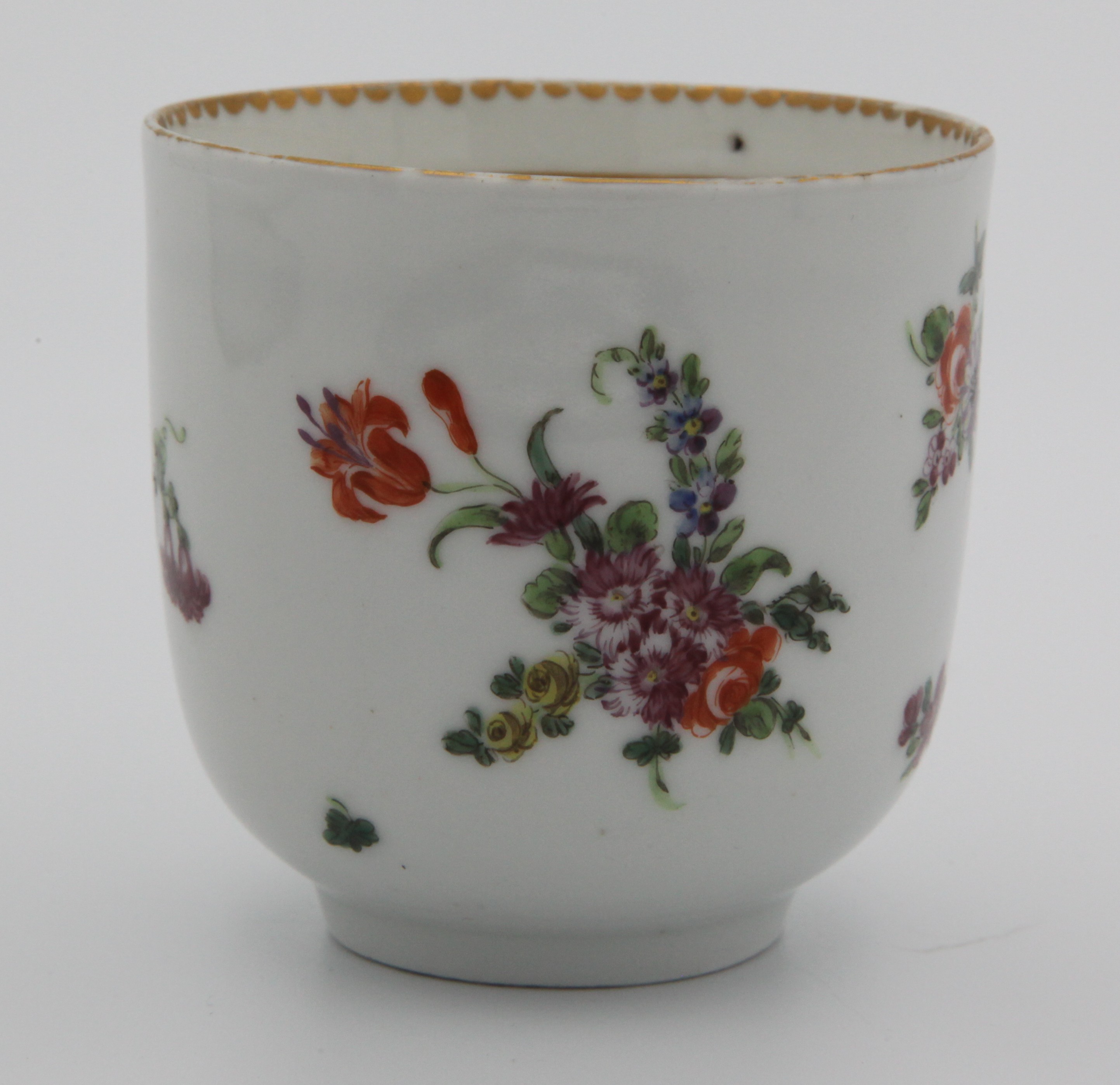A Bristol coffee cup with rounded twig handle, painted with scattered flower sprays and sprigs with solid and dentil gilt borders, circa 1775-80. No mark.