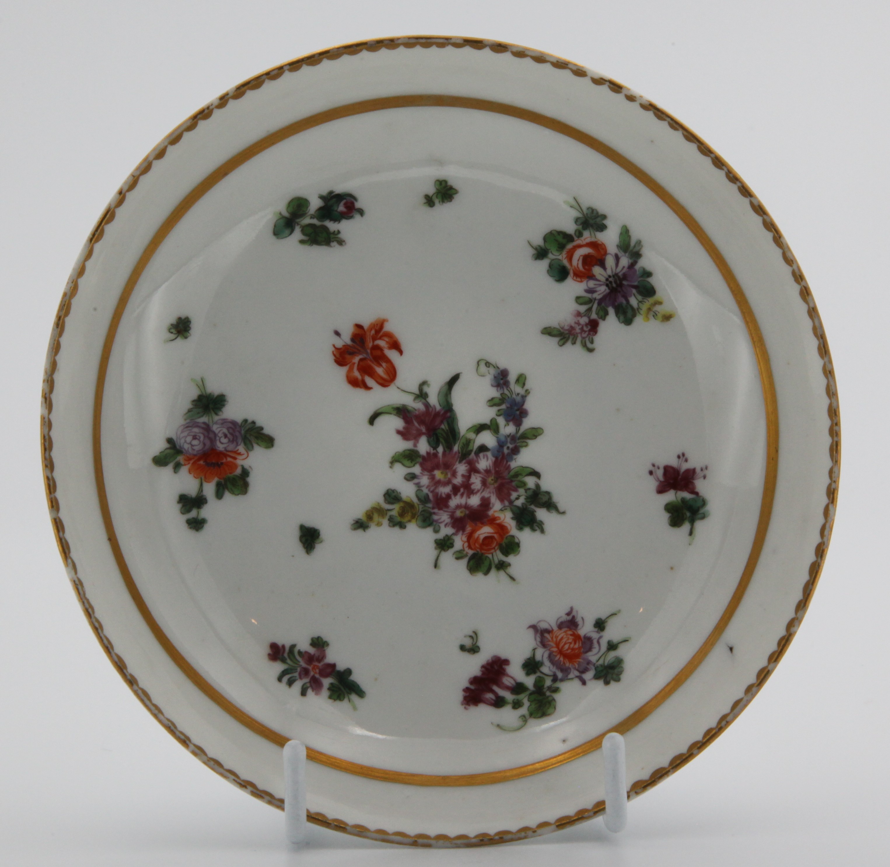 A Bristol saucer painted with a central spray and scattered sprigs and two gilt borders c. 1773-75  Mark: none. Paired with 1389