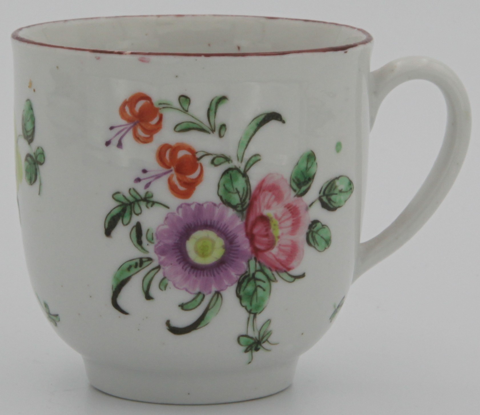 A Bristol coffee cup with plain handle, painted with a spray of purple, pink and two orange flowers, the reverse with scattered flowers and leaves, and an iron red line rim. Marked with blue X and numeral 7. painted in blue to base. Circa 1775