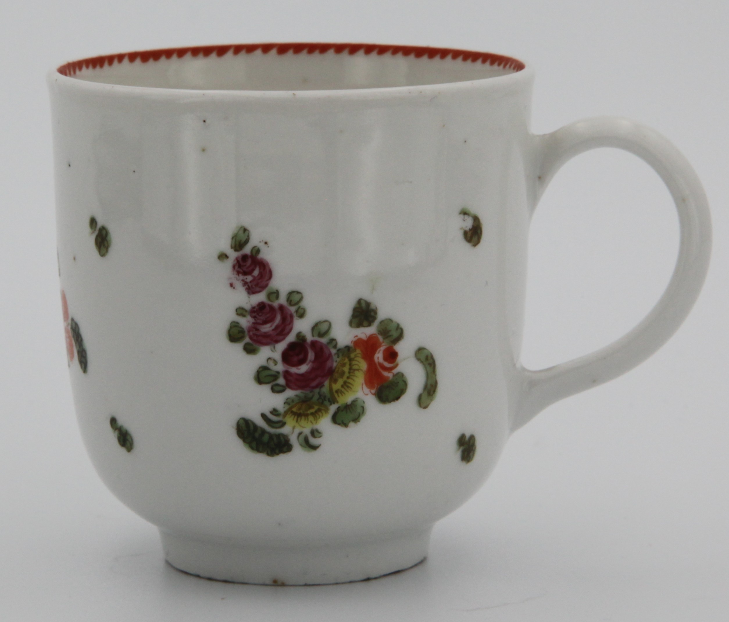 A Bristol coffee cup of plain form with simple handle painted with scattered pink and orange flowers, angular orange dentil rim c. 1775-78. Mark: none.