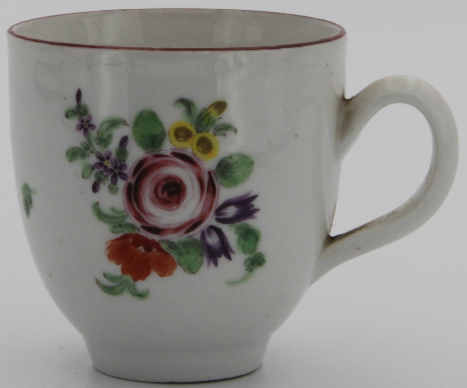 A Bristol coffee cup with plain handle, painted with a spray of flowers around a rose and scattered flowers and leaves under a brown line rim c. 1773-75. No mark