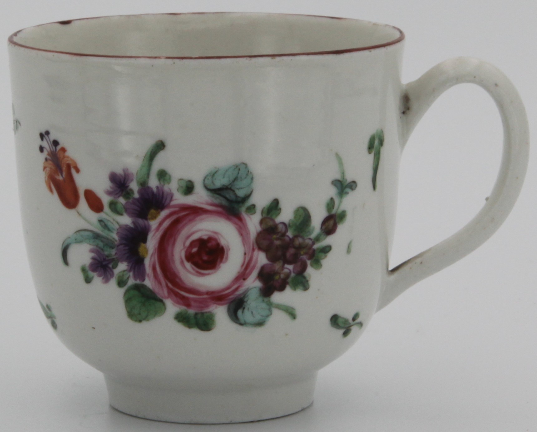 A Bristol coffee cup with plain handle, painted with a spray of flowers around a rose and scattered flowers and leaves under a brown line rim c. 1773-75. No mark