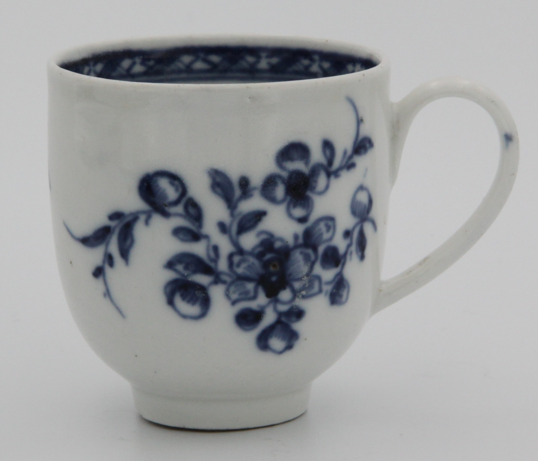 A small Bristol floral sprays pattern blue/white coffee cup with simple handle and with dark blue band to interior c1770.. Marked to the base with an underglaze blue x.