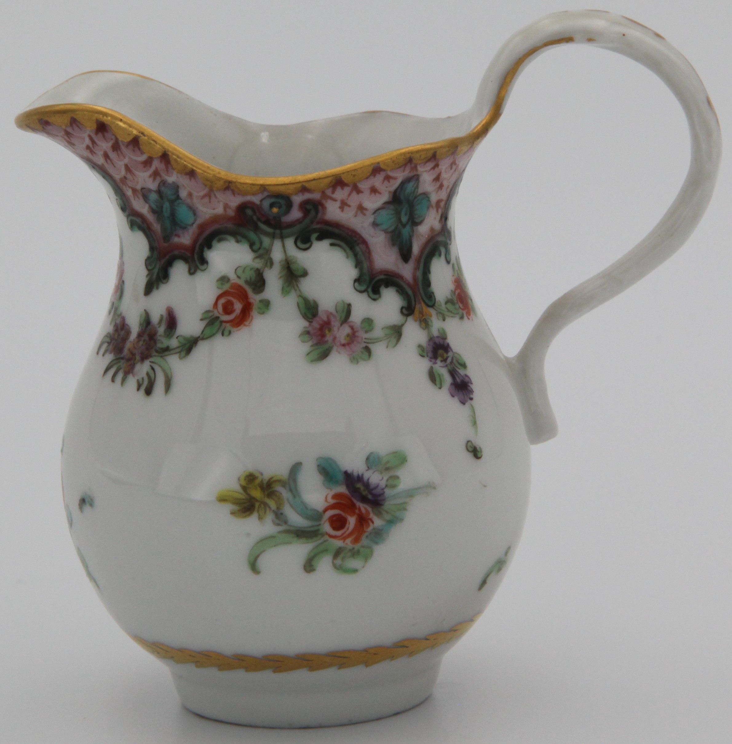 A baluster-shaped milk jug from a rare Bristol cabaret set, painted in coloured enamels with scattered flowers, within a pink scale border, with green ‘C’ scrolls and flower heads, suspending garlands of flowers and leaves, circa 1775.