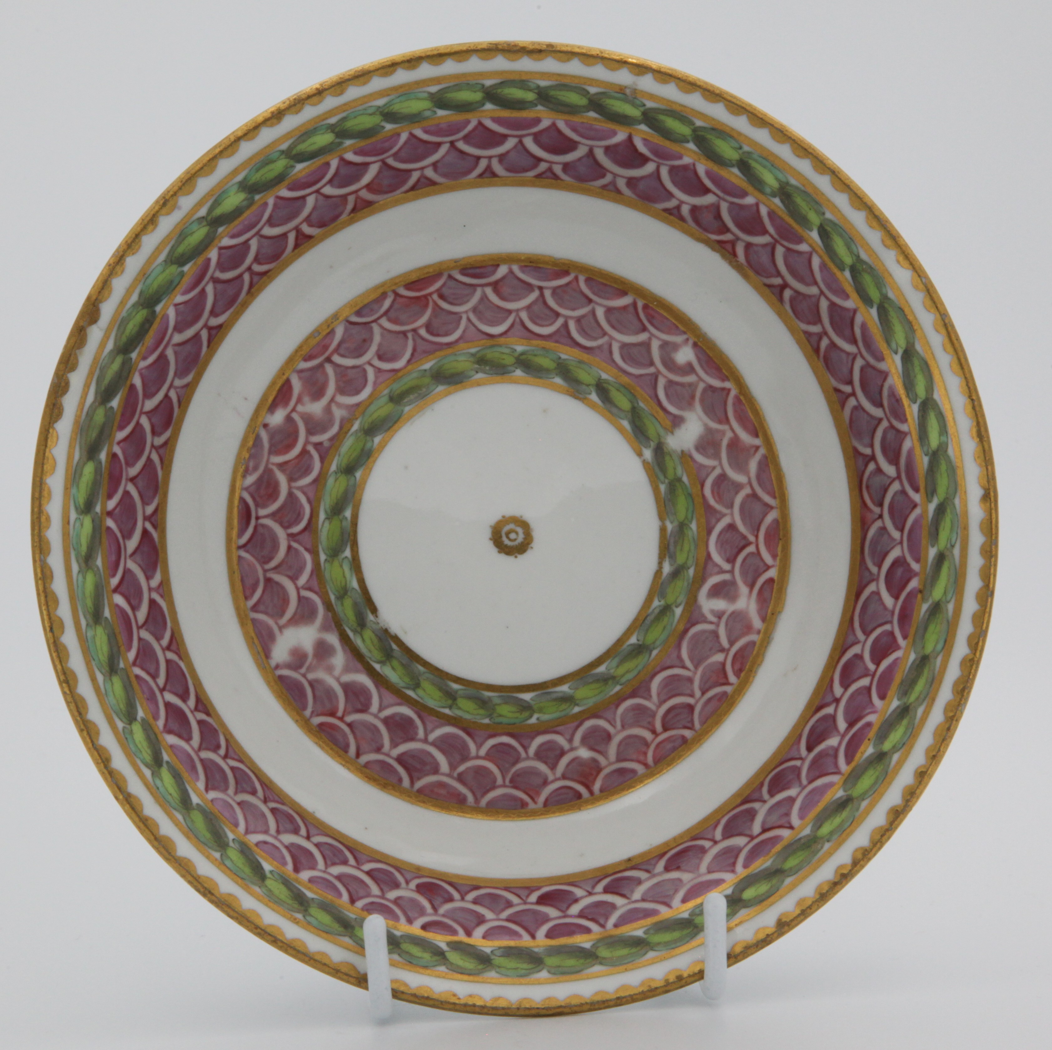 A fine Bristol coffee saucer, painted in pink with scale bands, within green laurel borders, gilt dentil rims, circa 1775, blue painted X4 on saucer. See Albert Amor Limited, The Alfred Trapnell Collection, 1912, numbers 27 and 28 for similar examples